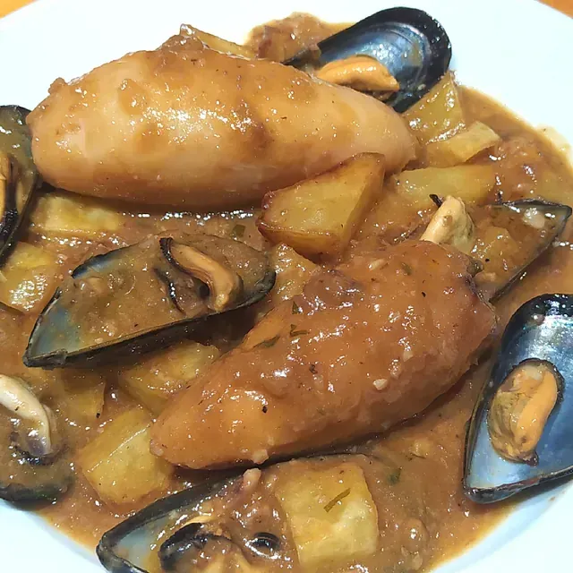 Un primer plano de un plato de comida con mejillones y patatas.