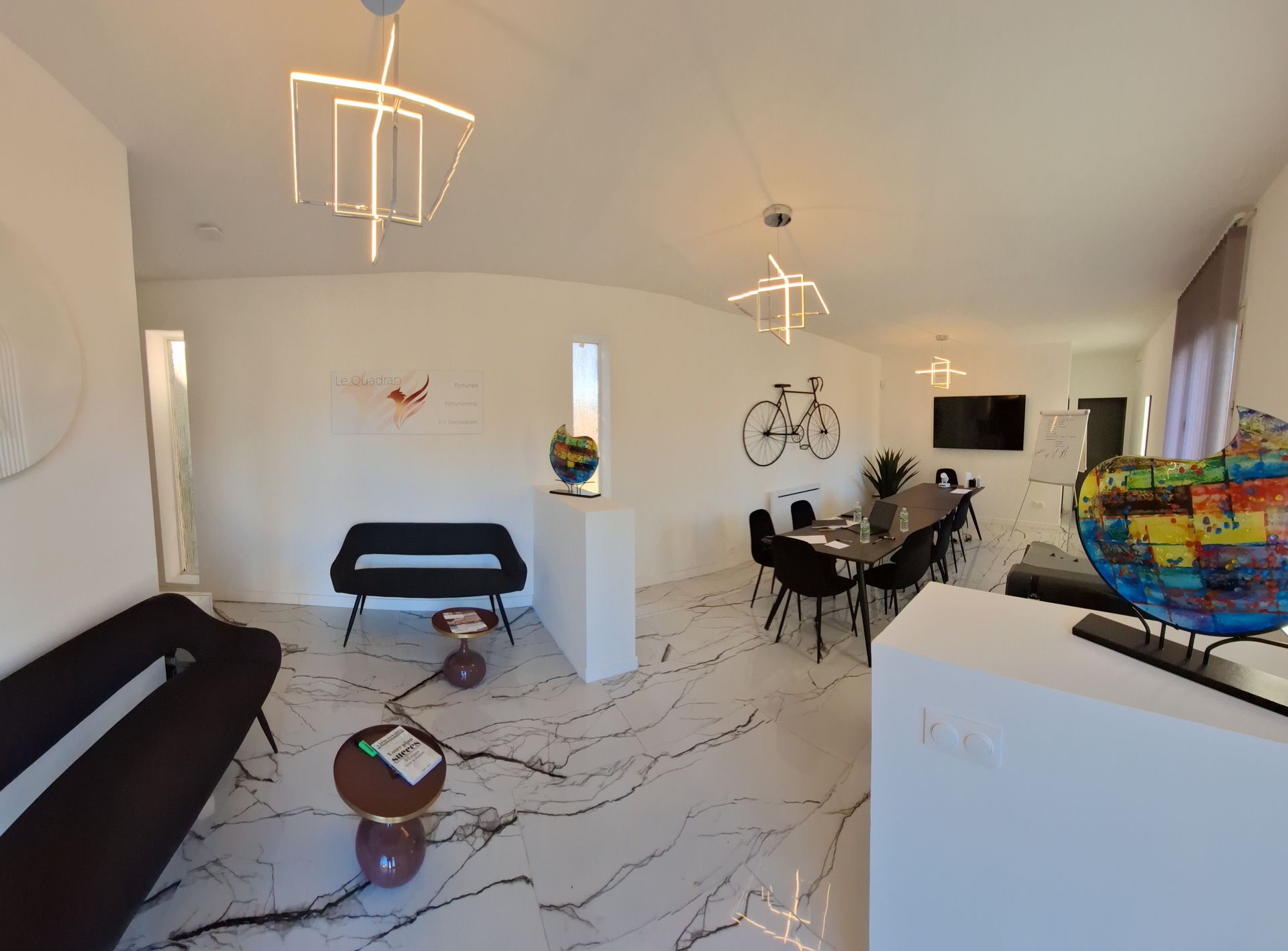 Intérieur de salon moderne avec murs blancs, mobilier noir, œuvres d'art et sol en marbre.