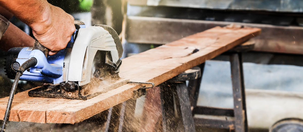 Un homme utilise une scie circulaire pour couper un morceau de bois.