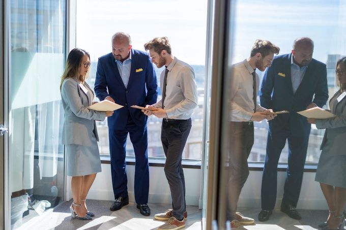 Empresarios revisando documentos cerca de una ventana. La luz del sol los ilumina.