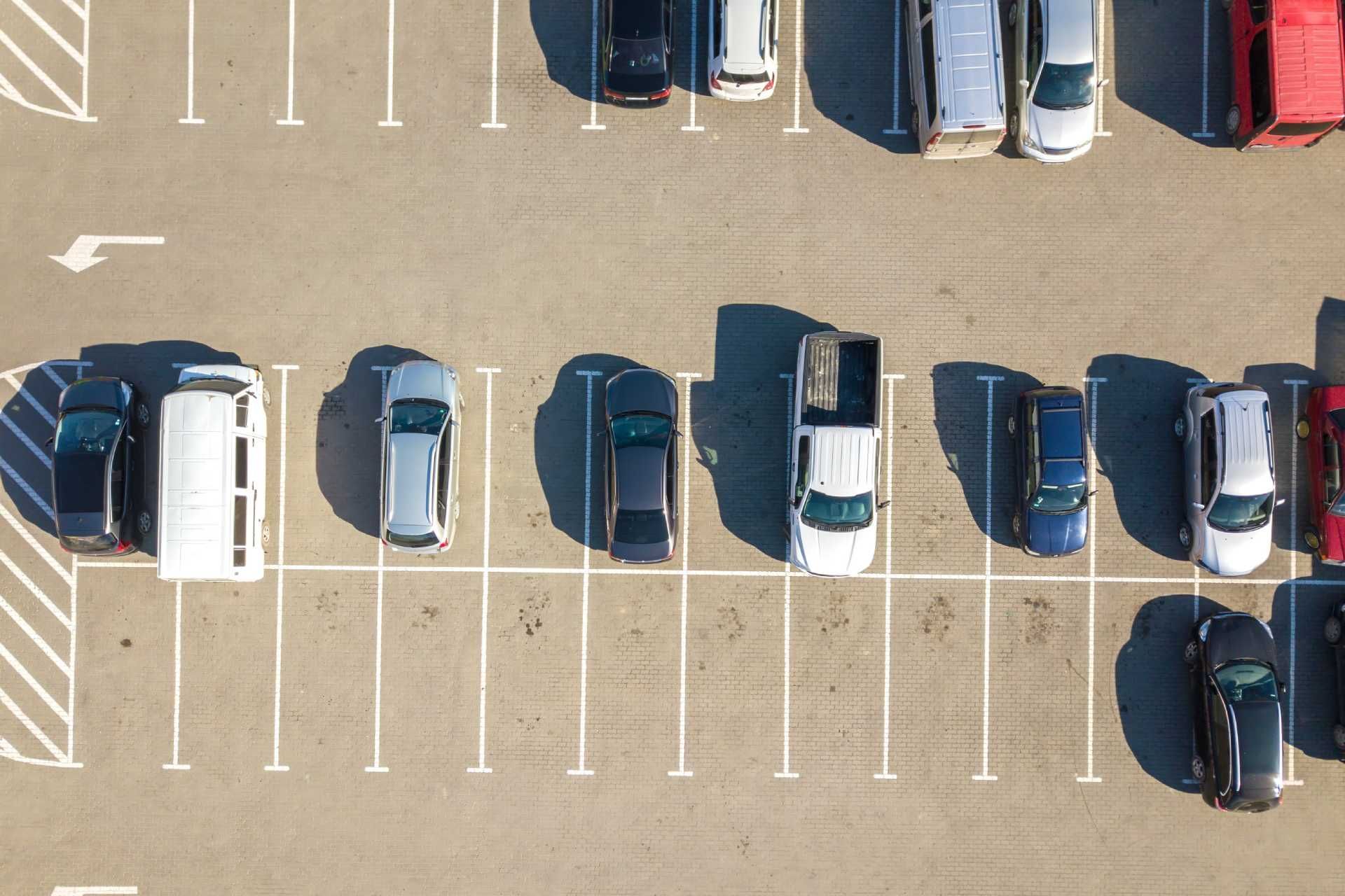 Vista aérea de un estacionamiento con autos estacionados en espacios marcados.