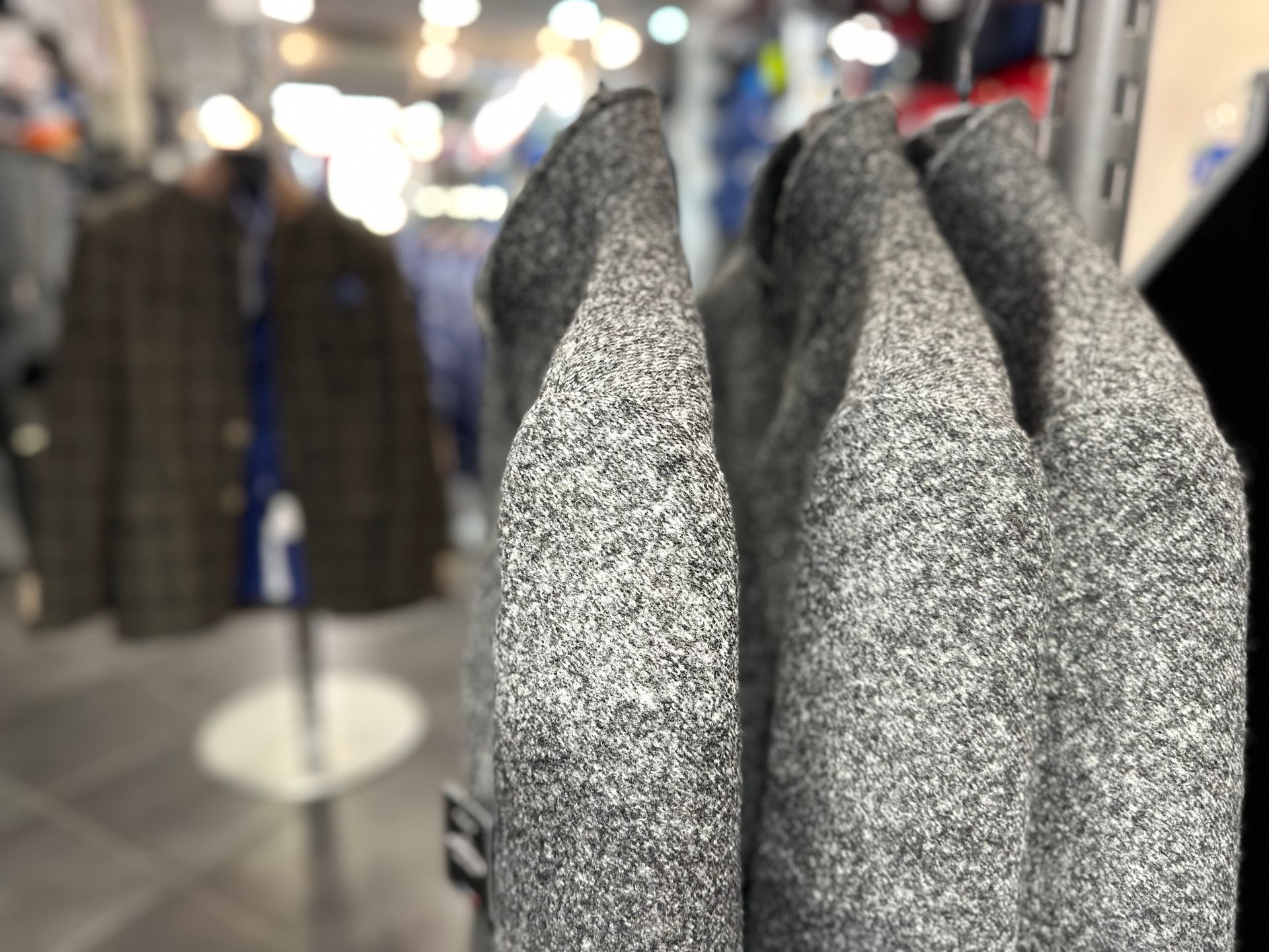 Manteaux gris sur les portants de la boutique à Nice