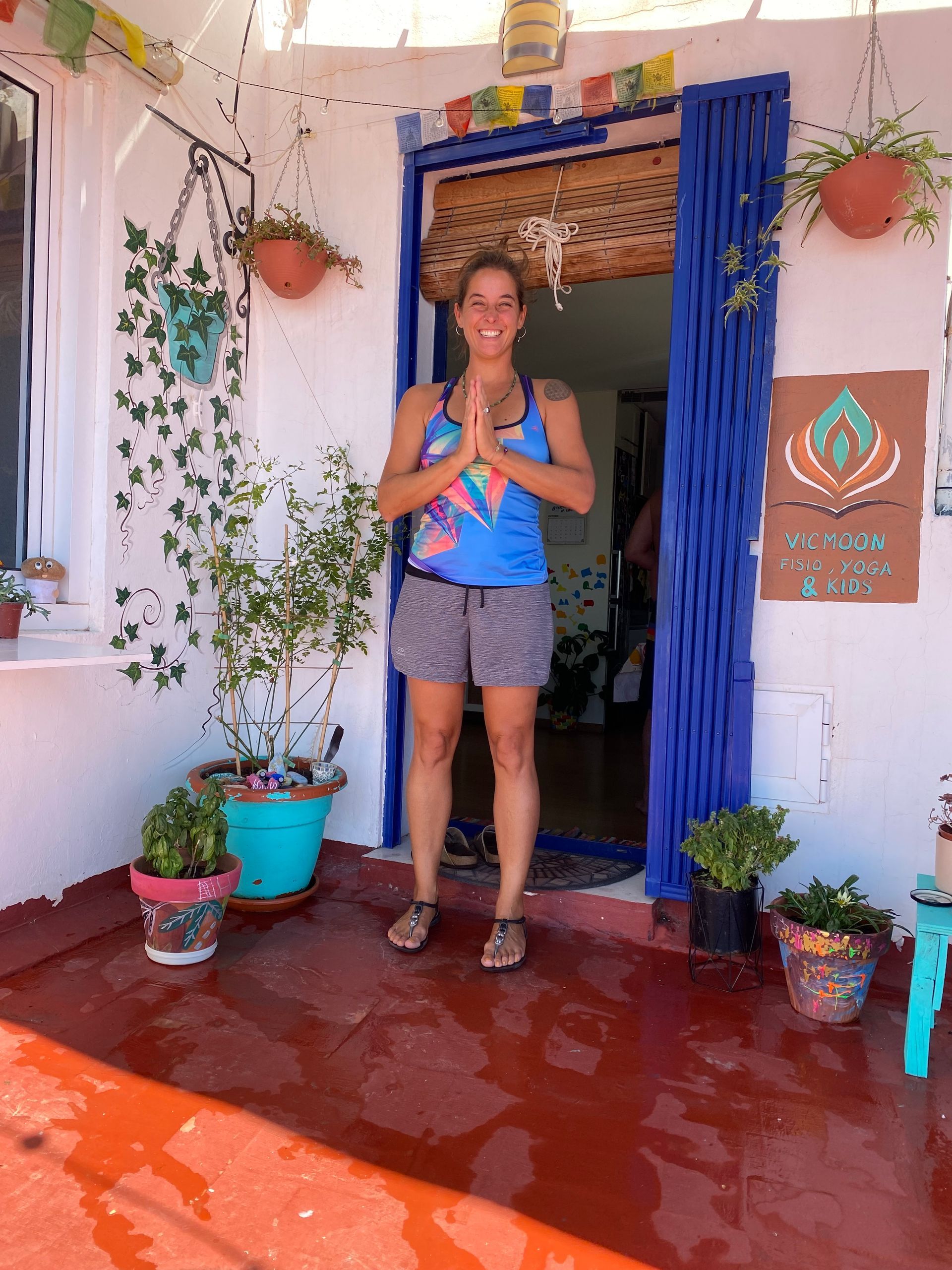 Una mujer con una camiseta azul y pantalones cortos está parada frente a una puerta.