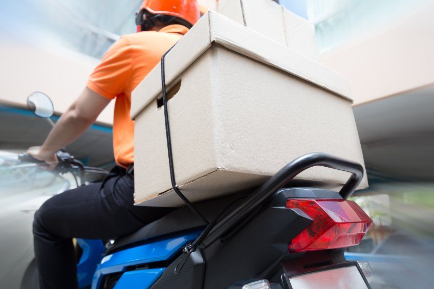 Un repartidor va en una motocicleta con cajas en la parte trasera.