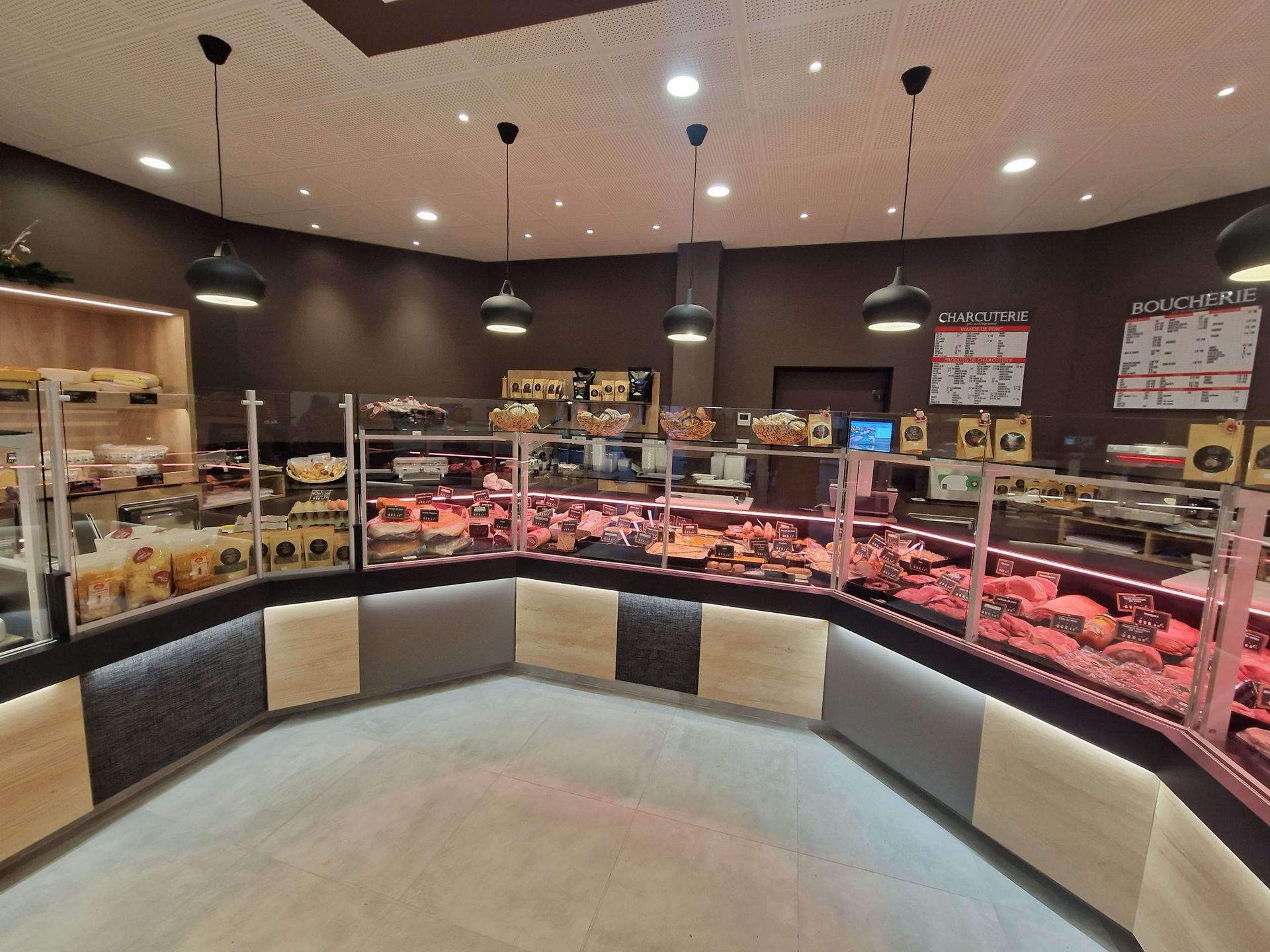 Intérieur d'une épicerie fine avec une longue vitrine remplie de viandes et de plats préparés variés ; design moderne.