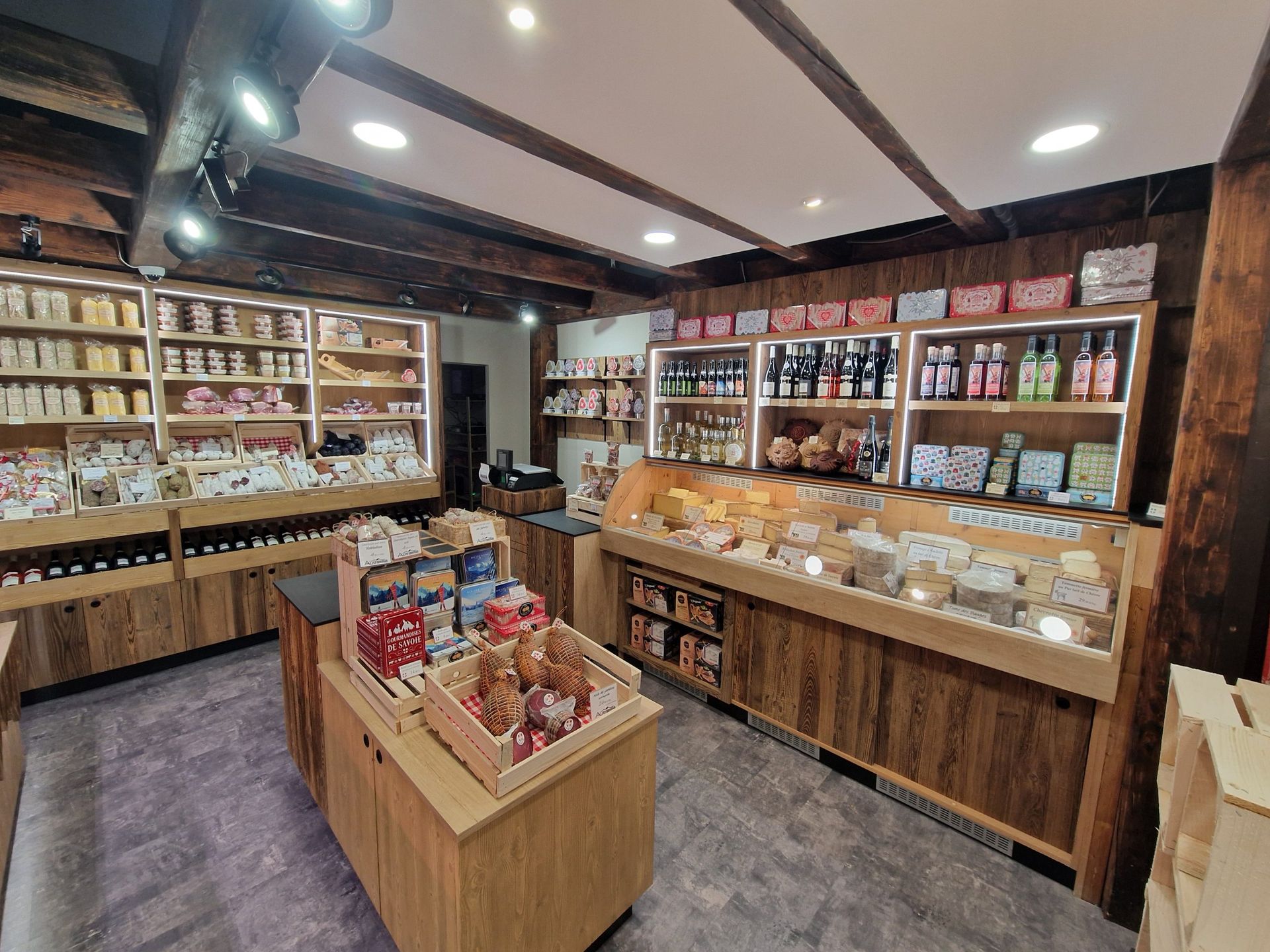 Intérieur d'un magasin d'alimentation spécialisé avec étagères en bois, vitrines et produits variés.