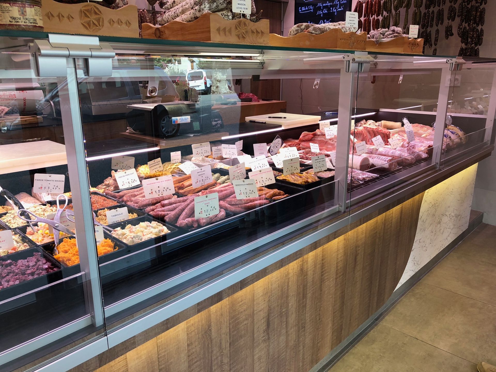Vitrine de viande dans une boucherie, présentant différentes coupes de viande avec leurs prix.