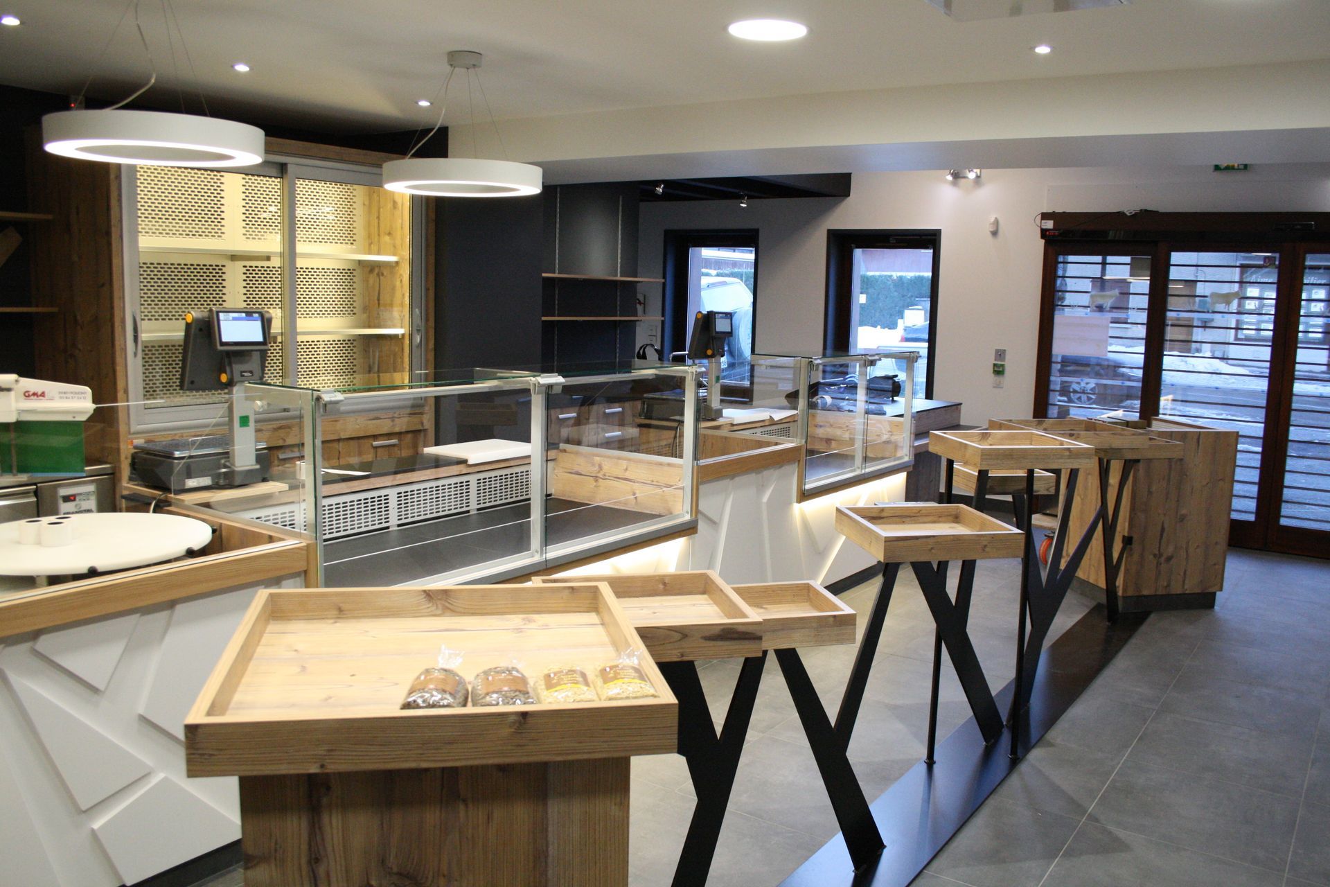 Intérieur d'un magasin moderne avec présentoirs en bois, comptoirs en verre et éclairage zénithal.