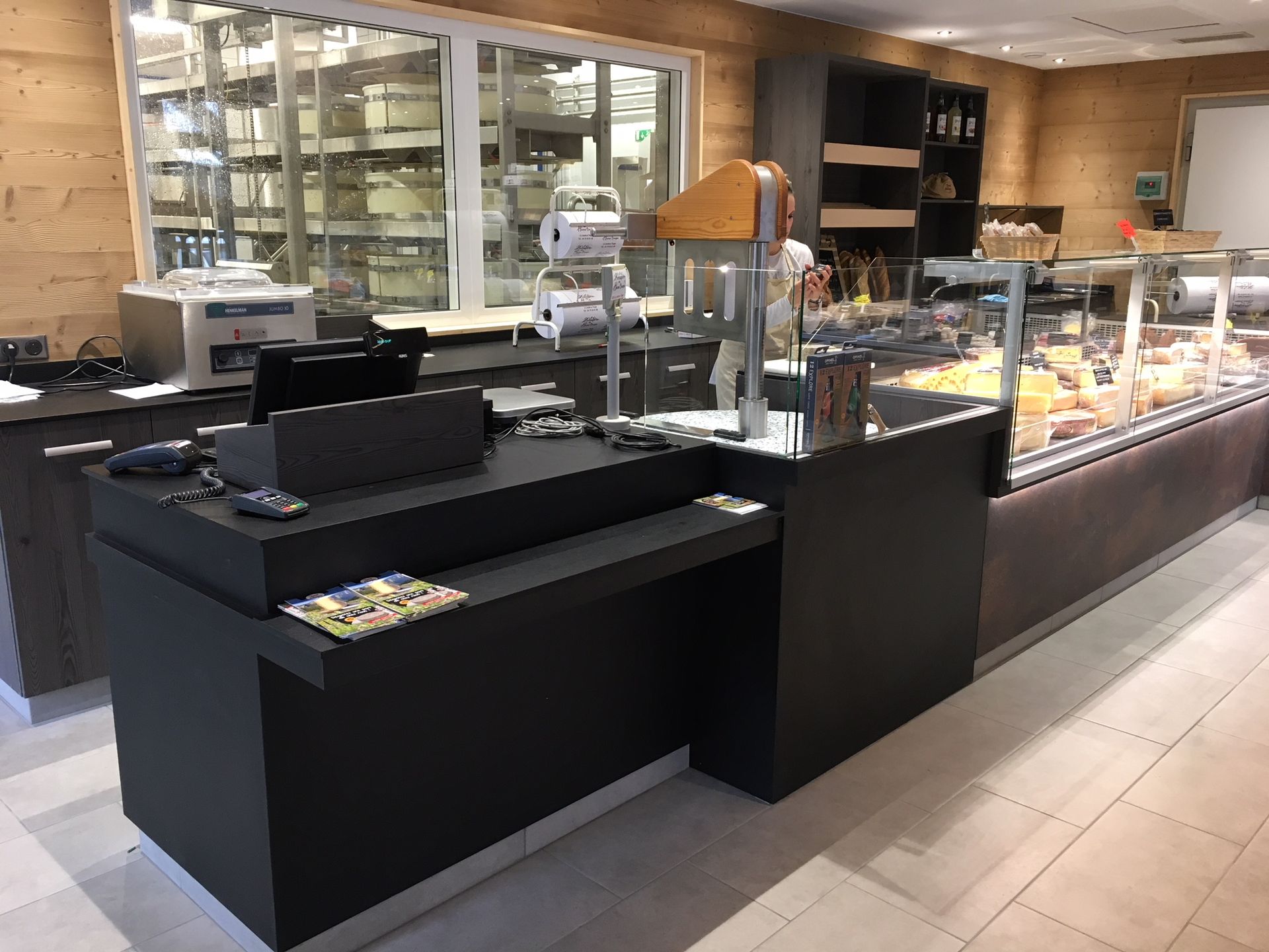 Comptoir noir dans un magasin avec vitrine de produits alimentaires et vitrine avec étagères.