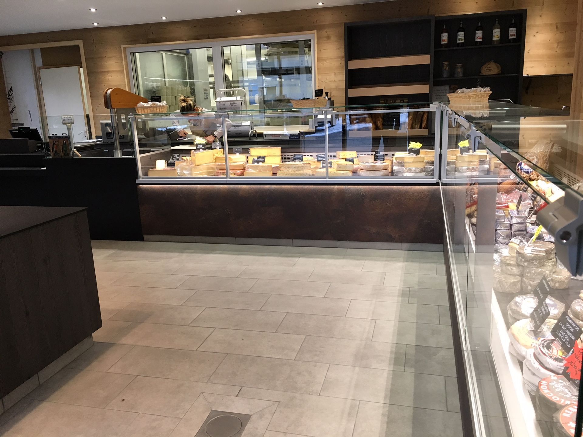 Intérieur d'une fromagerie avec une vitrine remplie de fromages variés.