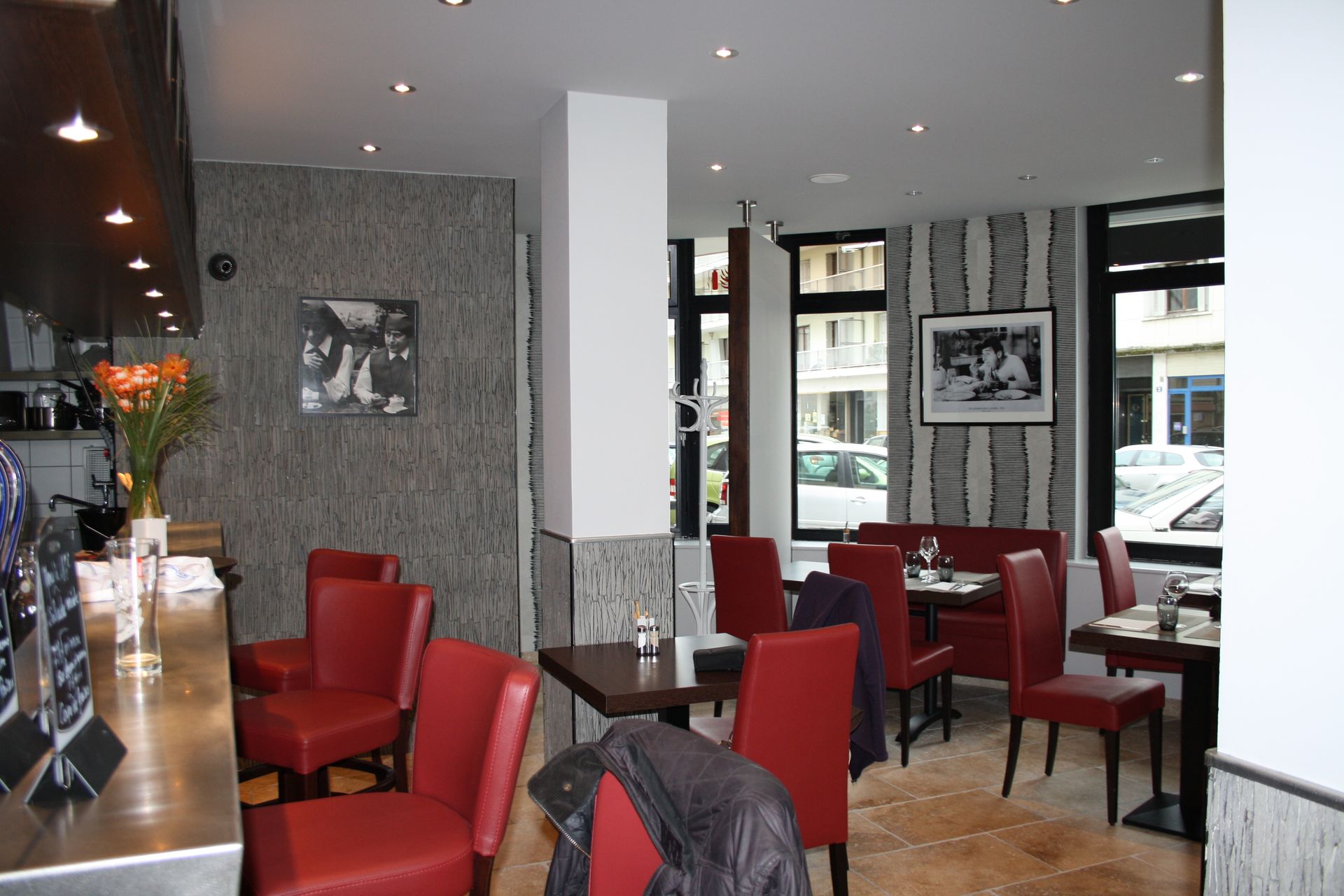 Vue intérieure d'un restaurant avec des chaises et des tables rouges, et des murs texturés.