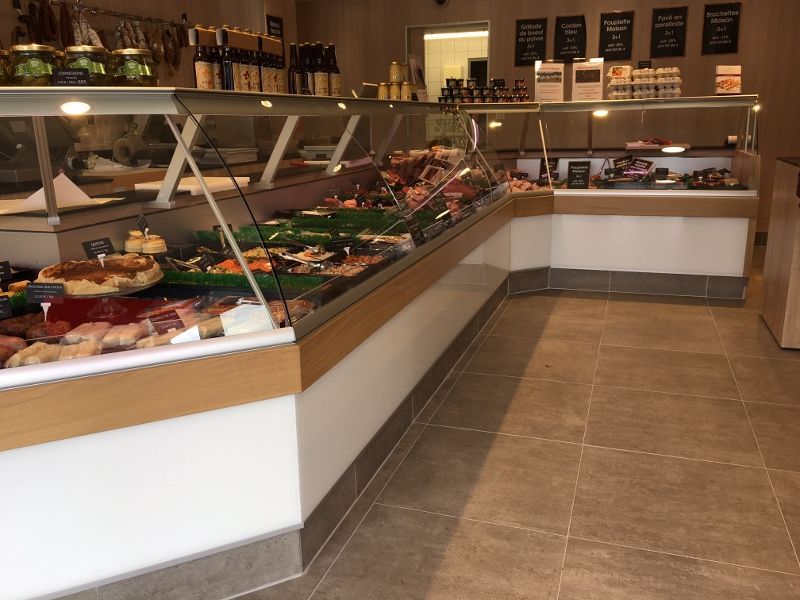 Intérieur d'une boucherie avec vitrines présentant viandes et plats préparés.