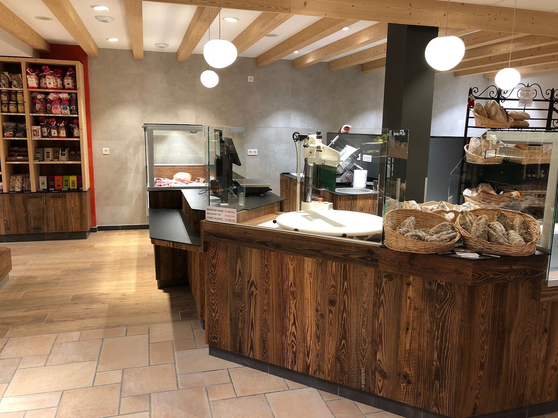 Intérieur d'une épicerie fine avec un comptoir en bois, des vitrines et des étagères remplies de produits.