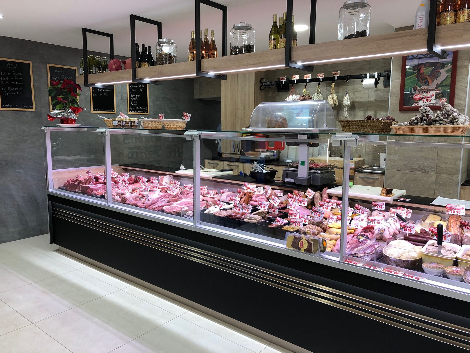 Vitrine de boucherie présentant diverses pièces de viande. L'exposition se fait derrière une vitre, au-dessus d'un socle noir.