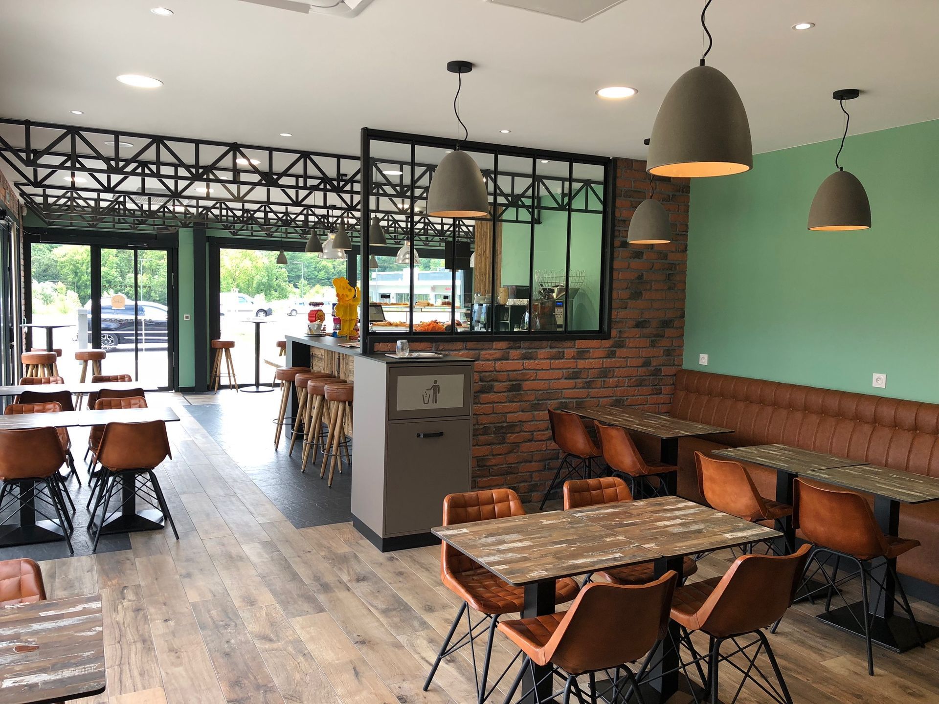 Intérieur d'un restaurant moderne avec tables, chaises et éléments en briques.
