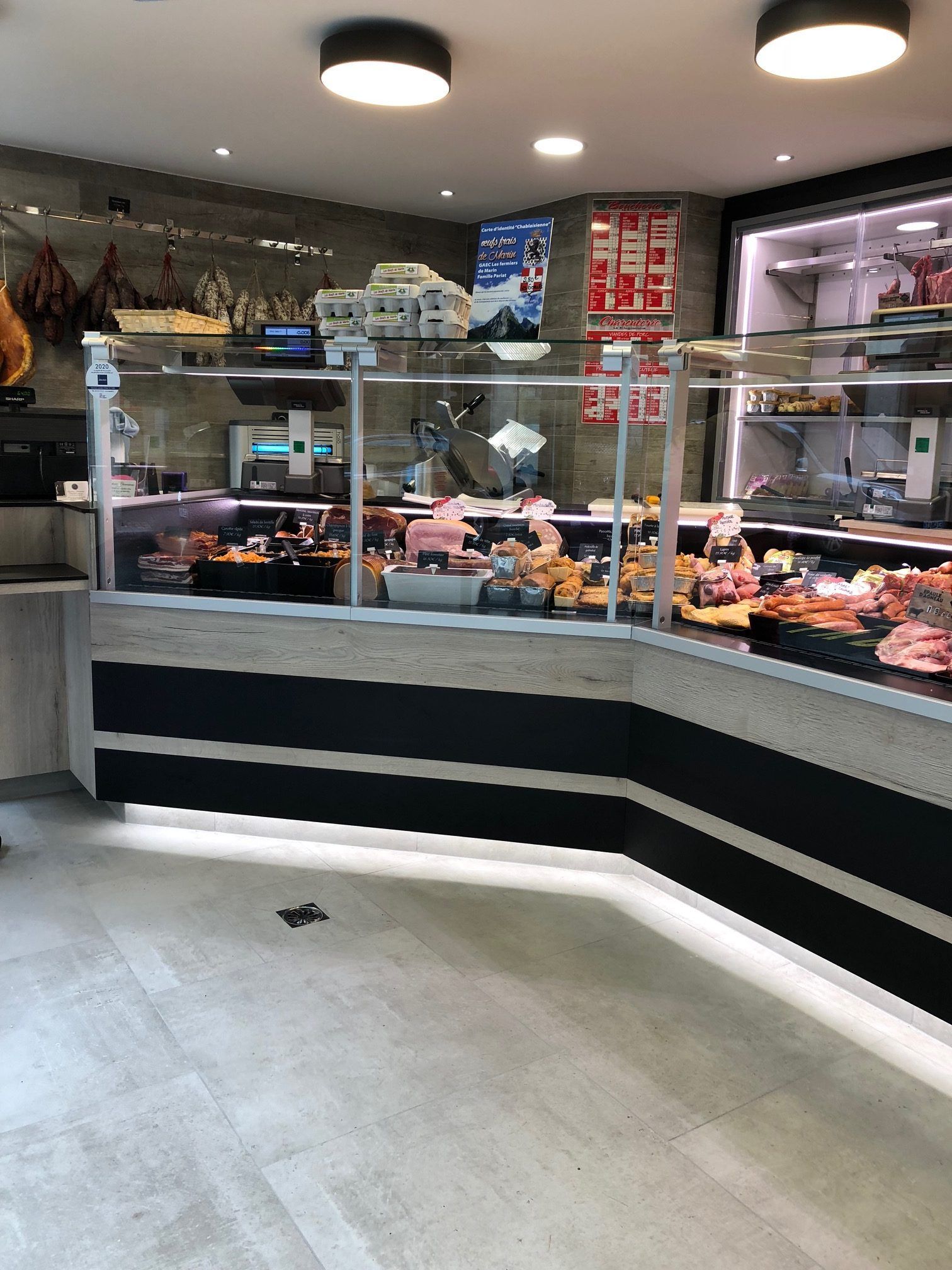 Boucherie avec vitrine remplie de produits carnés et comptoir noir et marron clair.