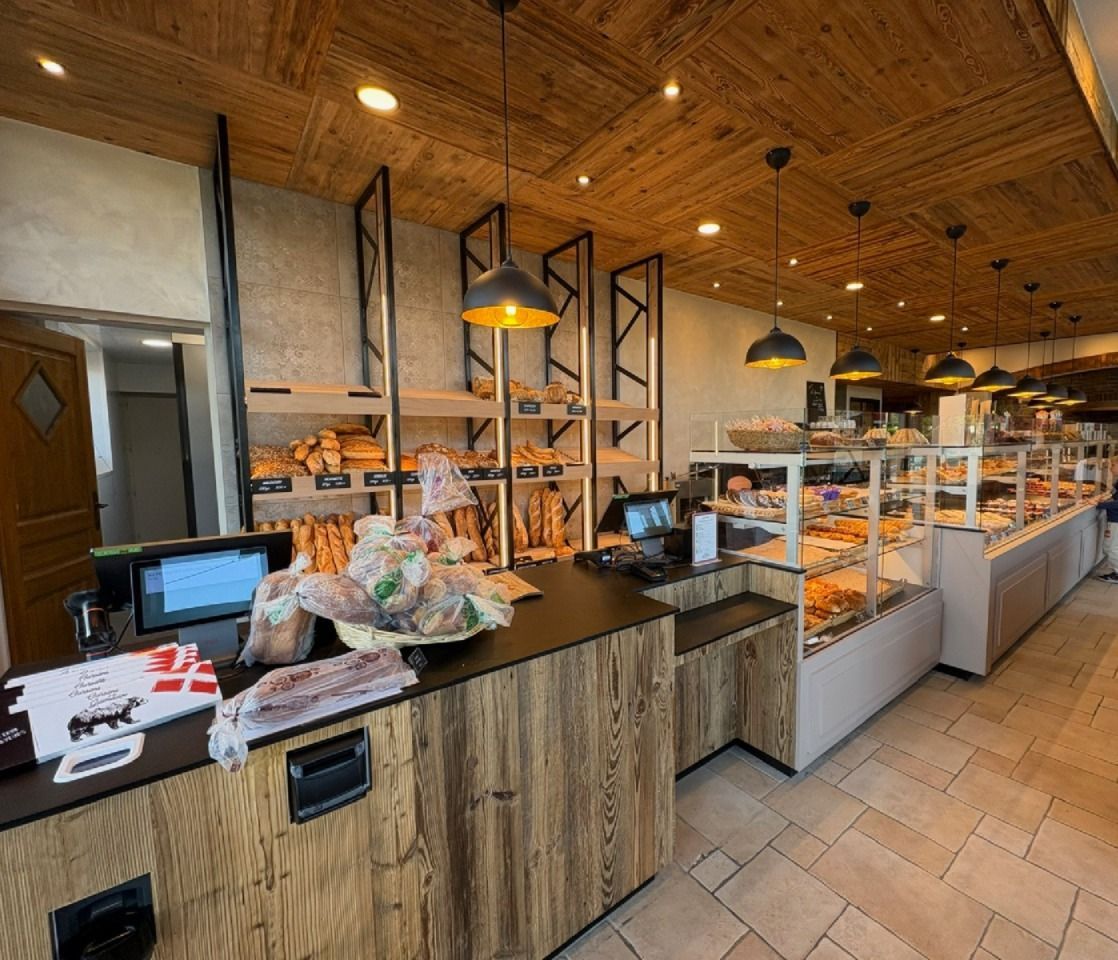 Intérieur d'une boulangerie avec présentoirs à pain, plafond en bois et comptoir.