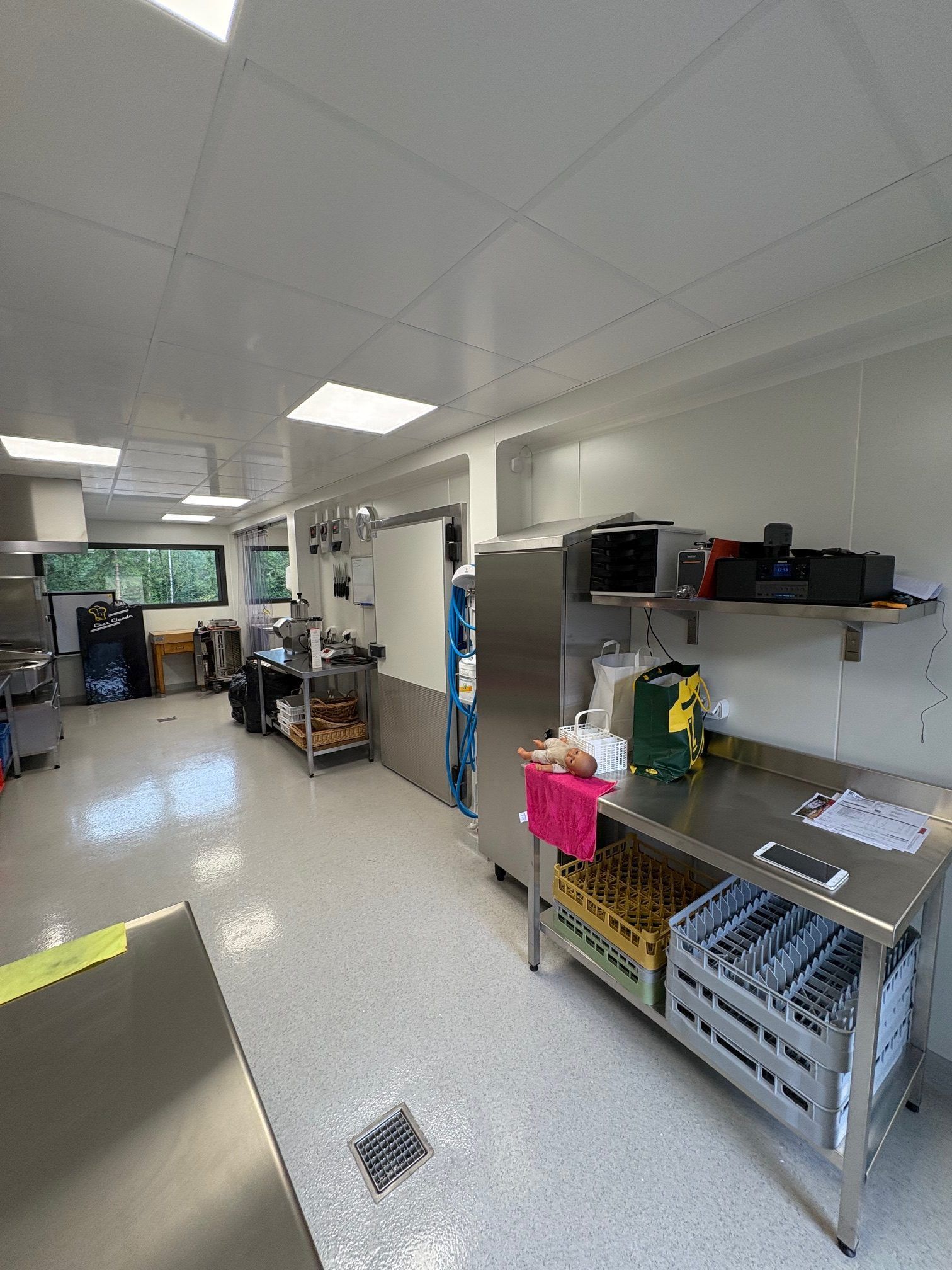 Cuisine commerciale avec comptoirs en acier inoxydable, appareils électroménagers et murs blancs.