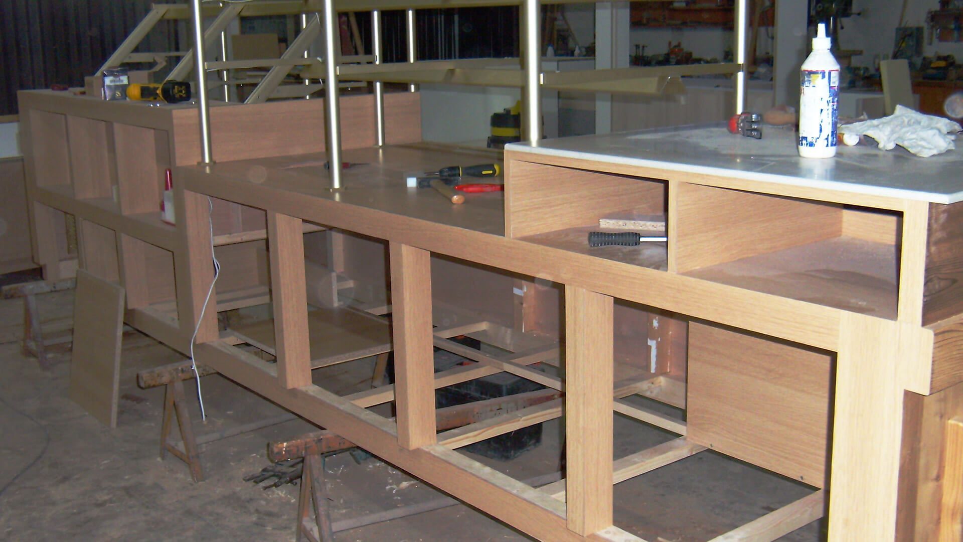 Construction d'un meuble en bois dans un atelier, avec charpente et étagères apparentes.