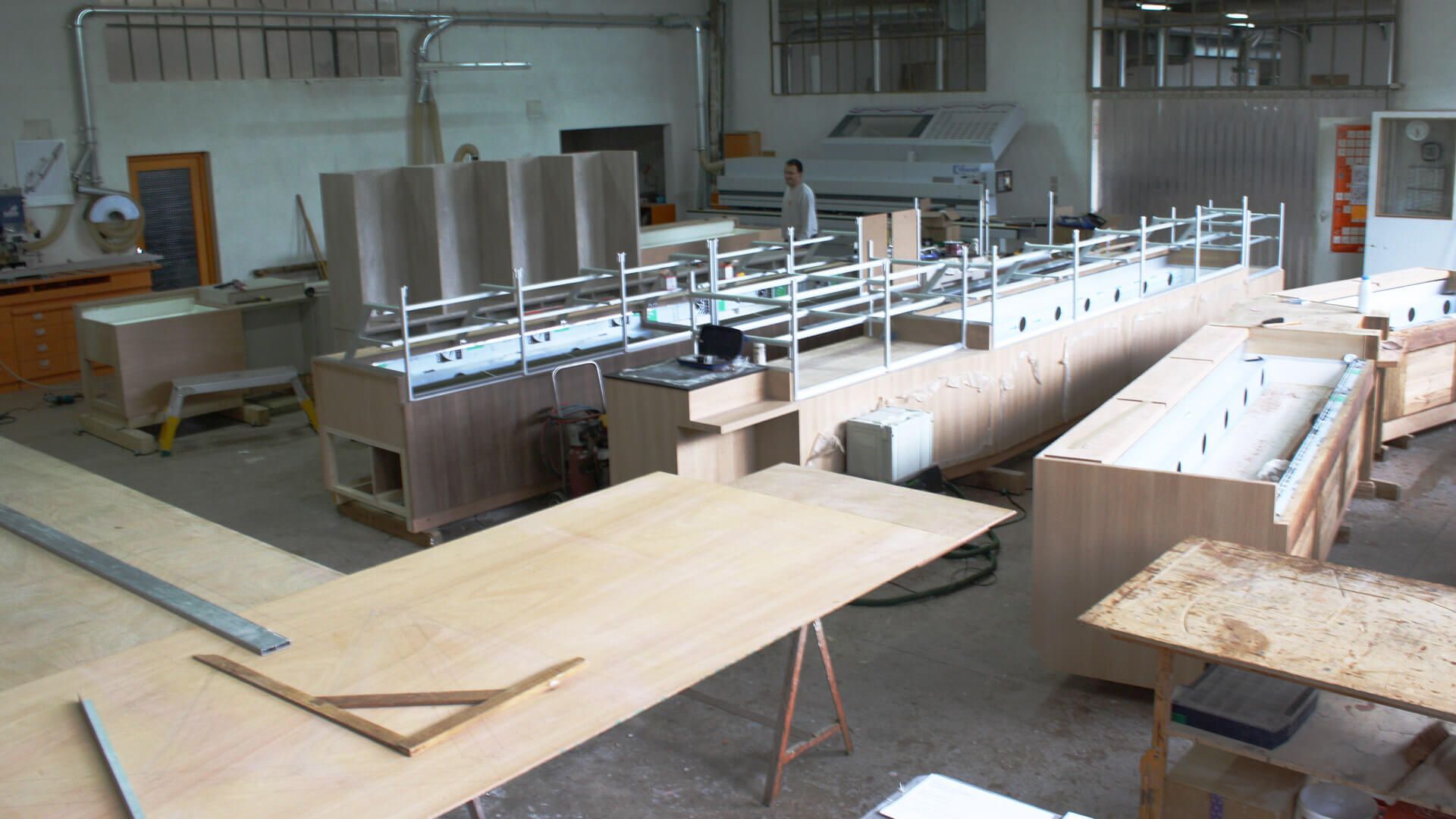 Intérieur d'atelier avec machines à bois et grandes structures en bois en construction.