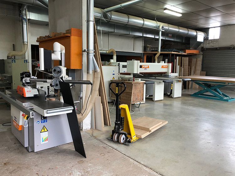 Un atelier de menuiserie équipé de machines, notamment une scie, un établi et un transpalette.