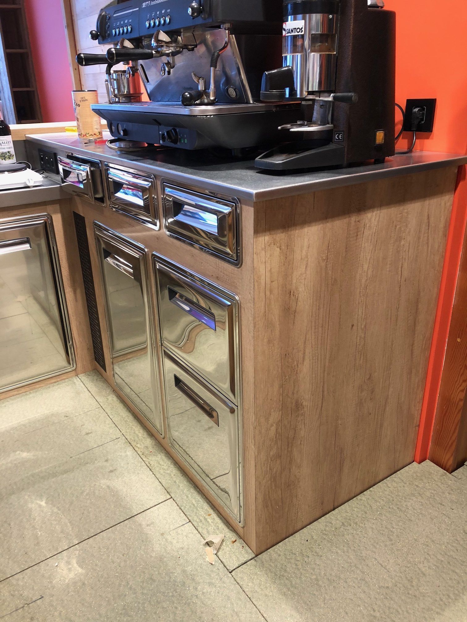 Machine à expresso sur un comptoir avec portes de réfrigérateur en acier inoxydable et panneaux de bois.