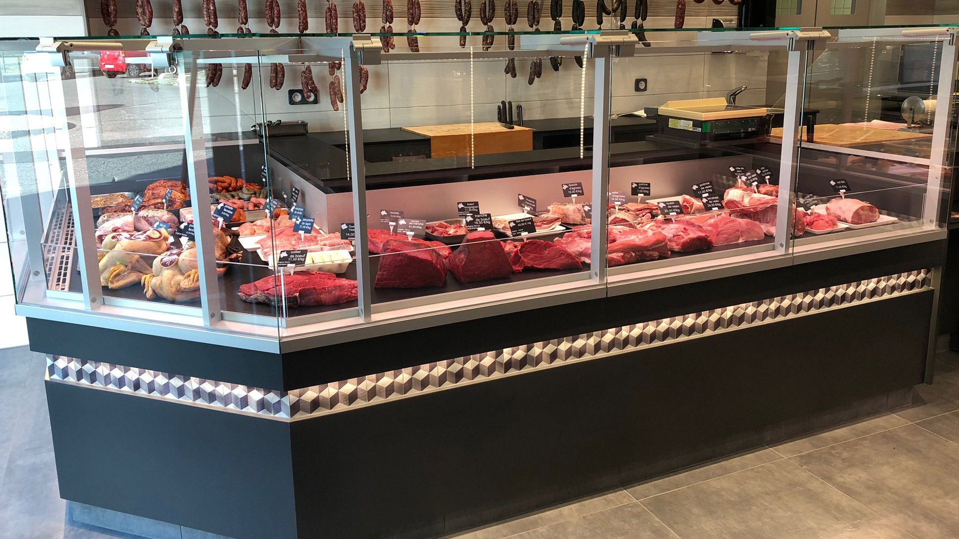 Vitrine à viande dans une boucherie, remplie de différentes coupes de viande crue.