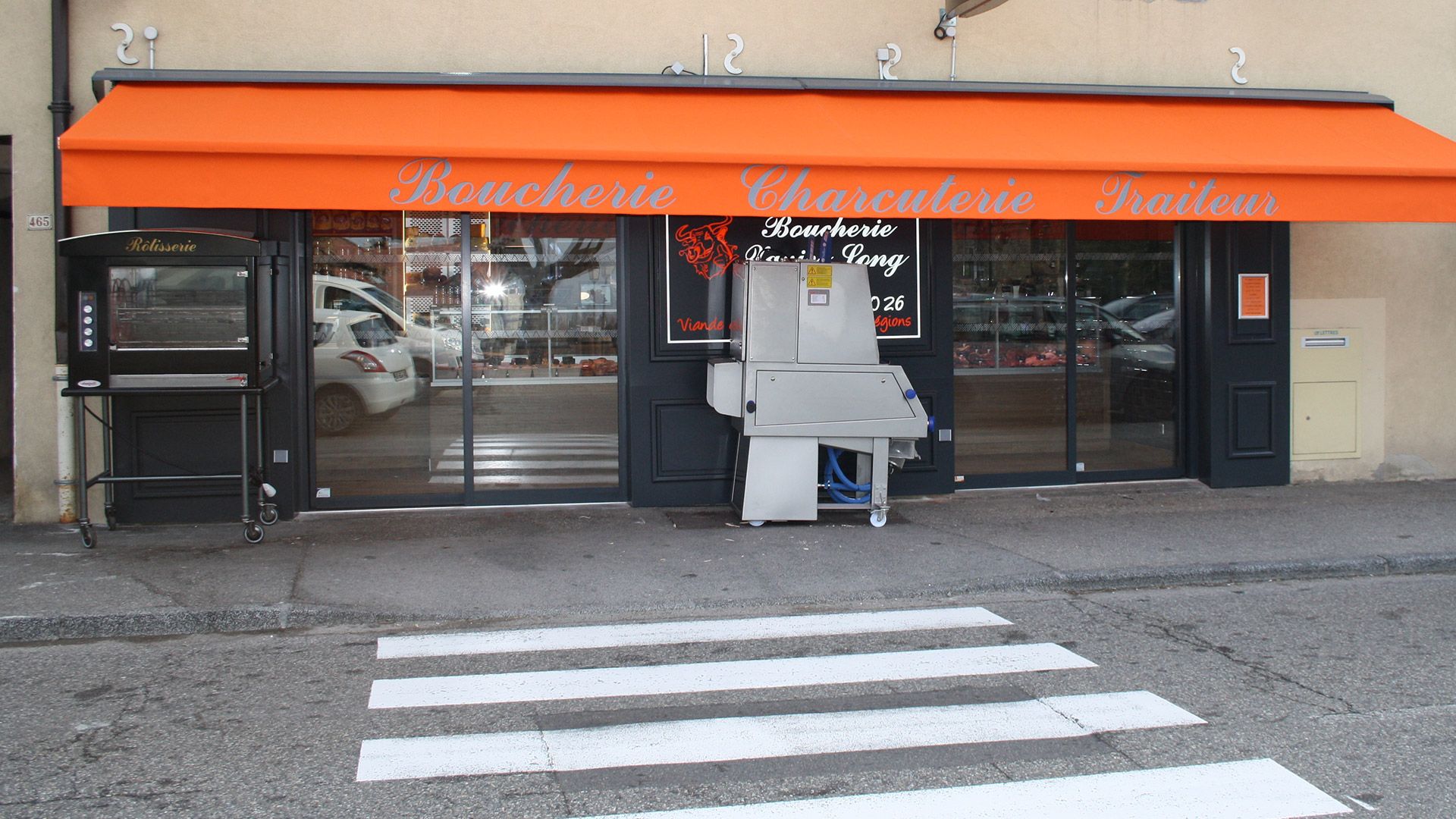 Boucherie avec auvent orange et passage piéton.