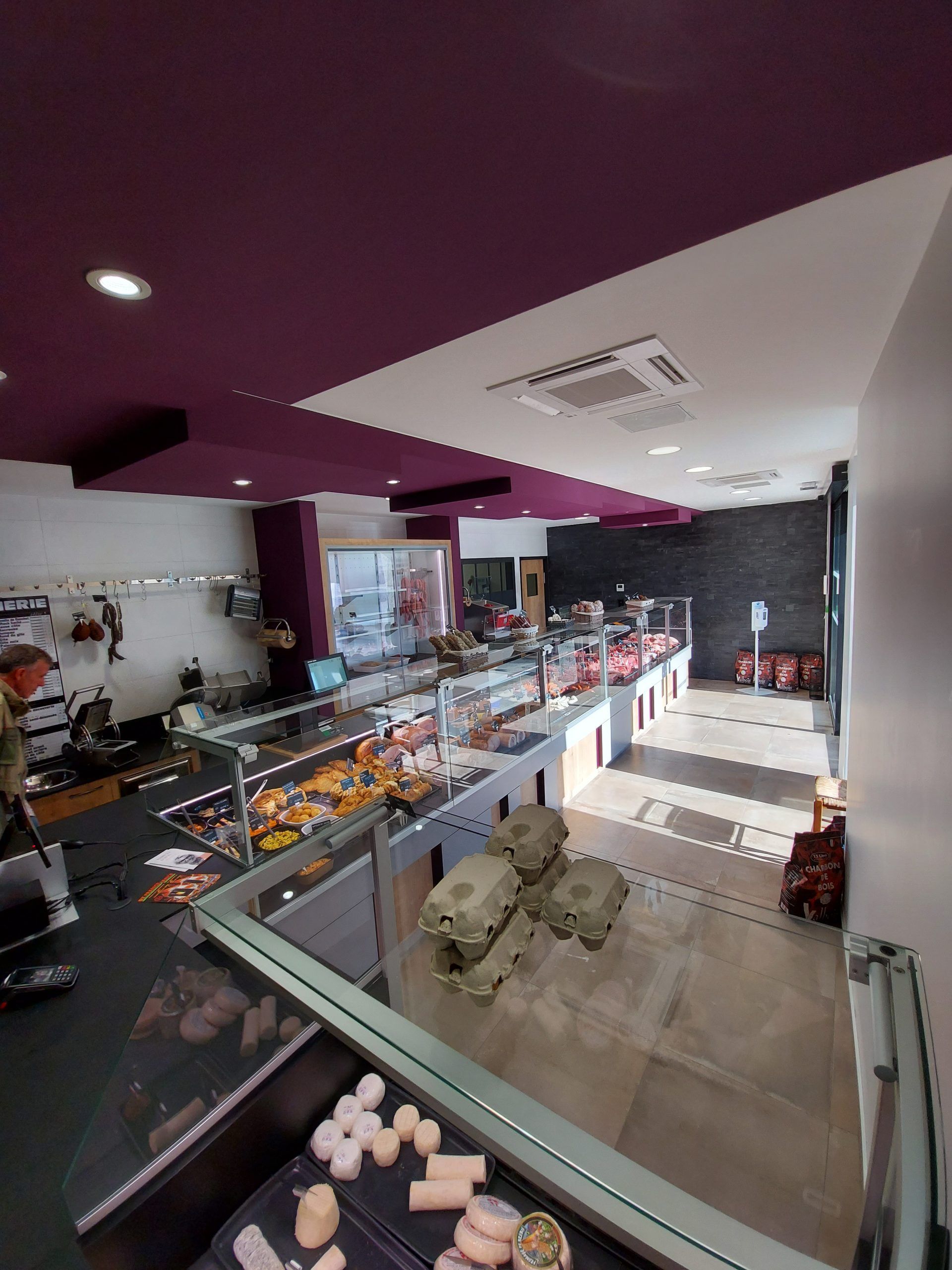 Intérieur d'une boucherie avec vitrines et comptoirs. Plafond violet et blanc.