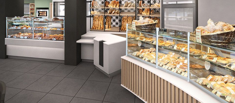 Intérieur d'une boulangerie avec des vitrines remplies de produits de boulangerie, notamment du pain, des viennoiseries et des croissants.
