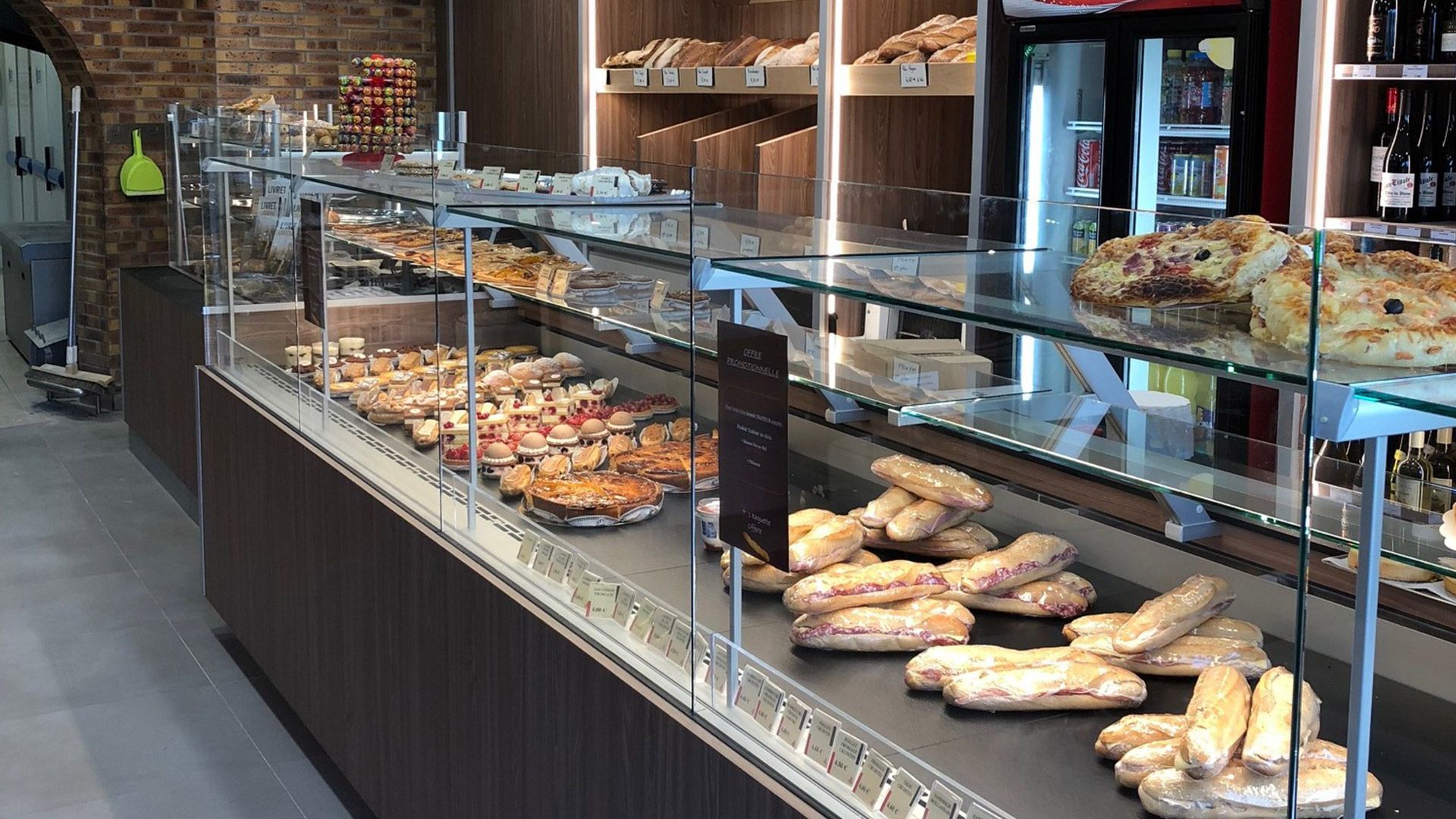 Vitrine de boulangerie présentant diverses pâtisseries et pains ; vue intérieure.