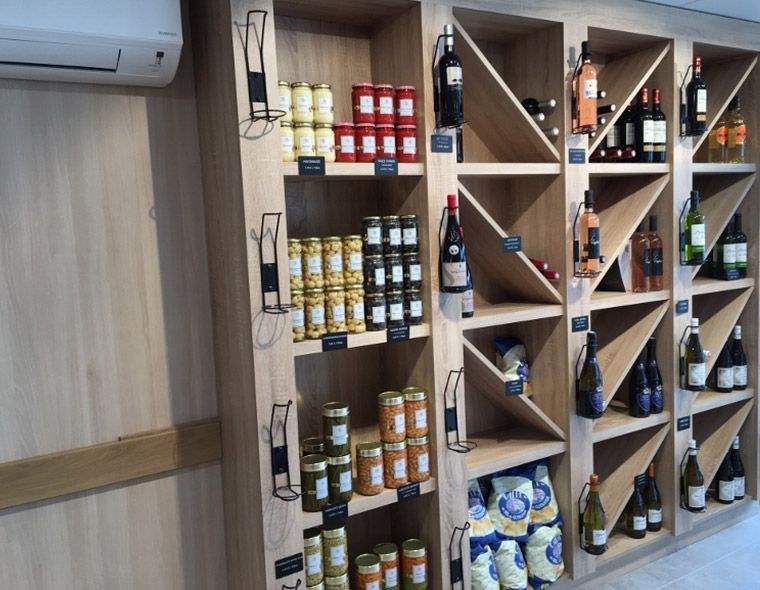 Des étagères en bois remplies de bocaux alimentaires et de bouteilles de vin.