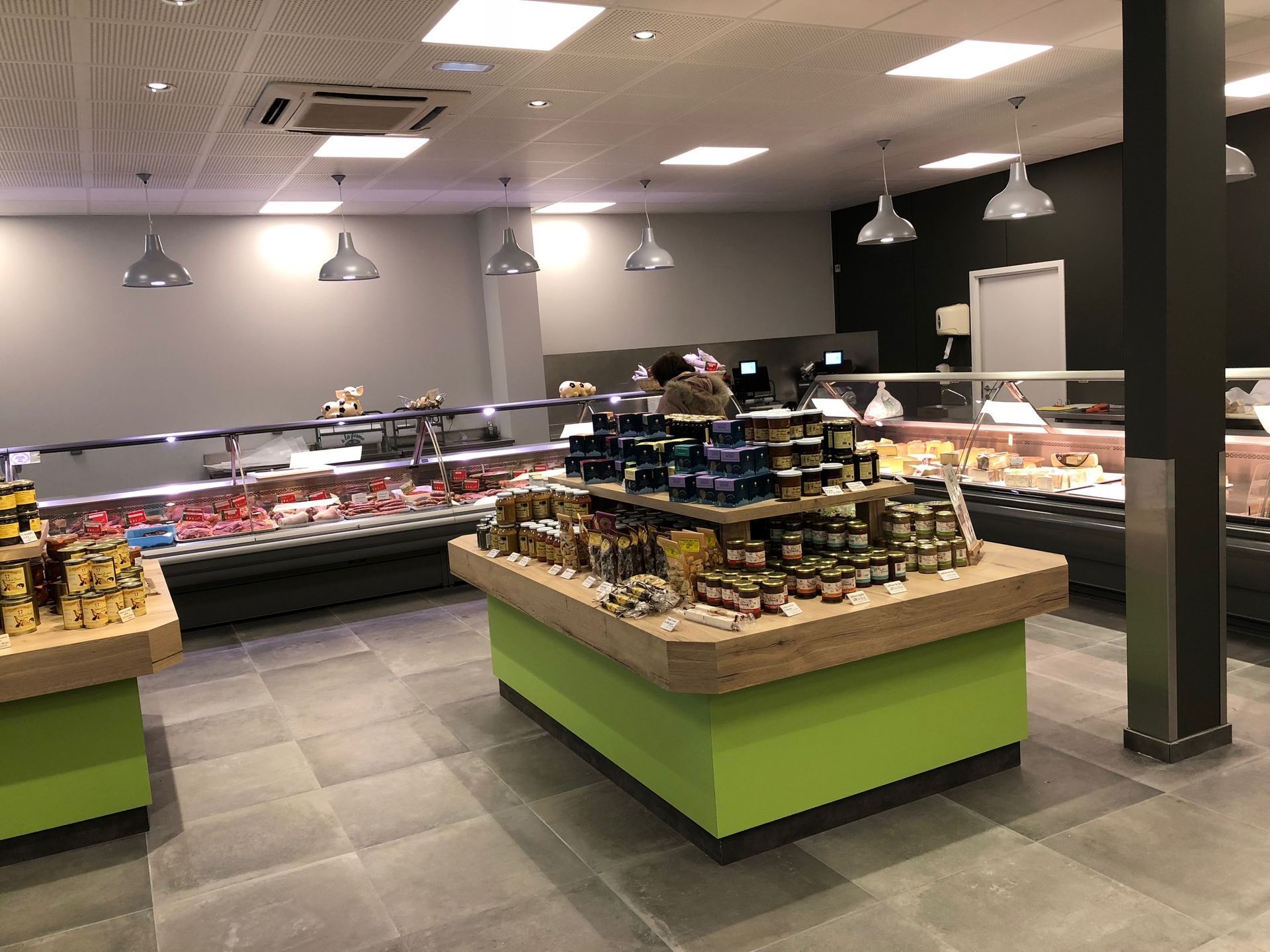 À l'intérieur d'une épicerie bien éclairée, la viande et d'autres produits sont présentés dans des vitrines réfrigérées et sur un îlot central.
