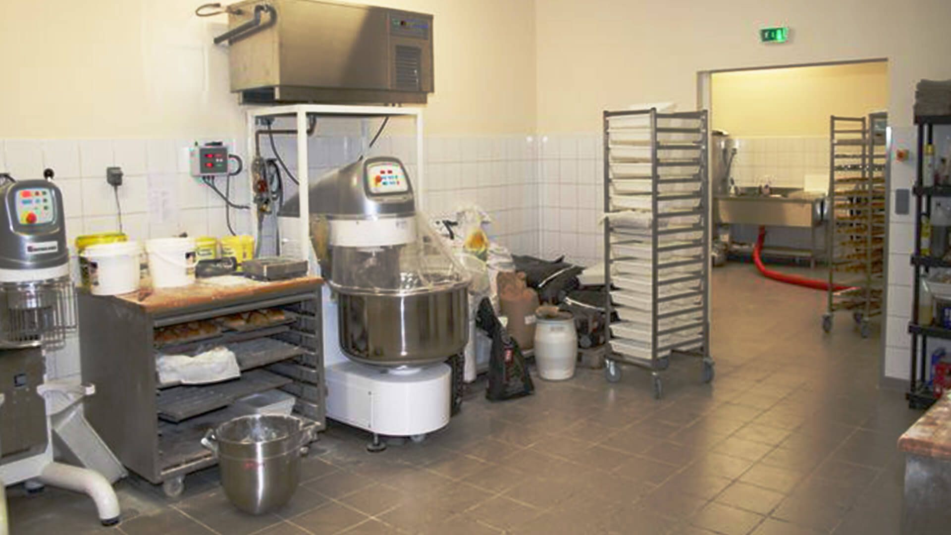 Cuisine de boulangerie commerciale avec équipement de mélange et étagère à plateaux.