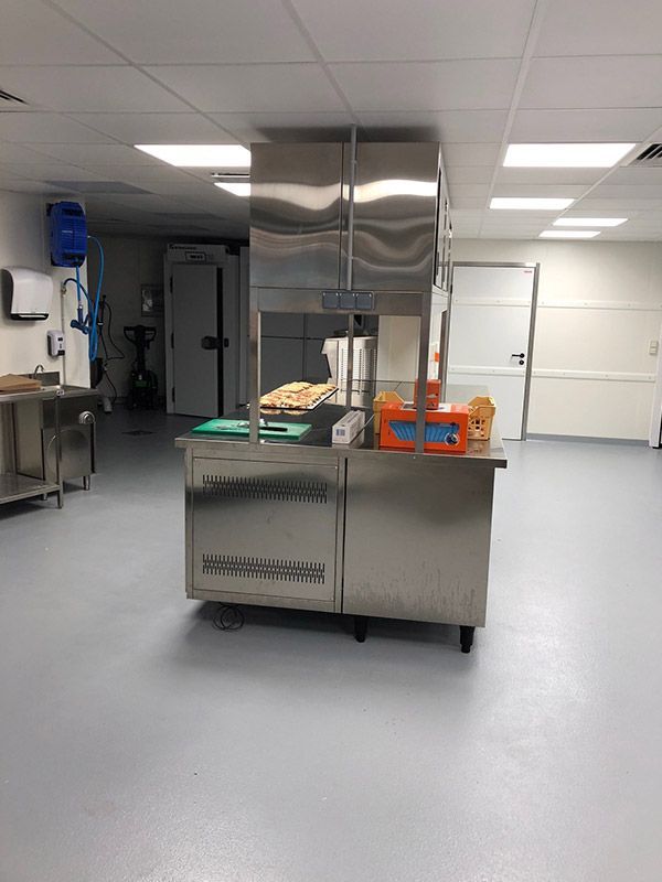 Poste de préparation alimentaire en acier inoxydable dans une cuisine professionnelle lumineuse.