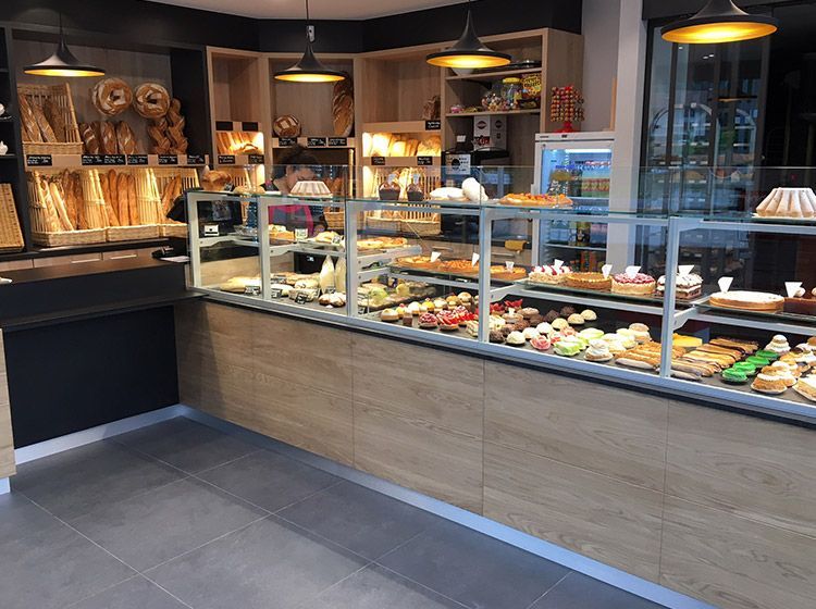 Vitrine de boulangerie présentant diverses pâtisseries, pains et produits de boulangerie. Étagères et comptoir en bois.