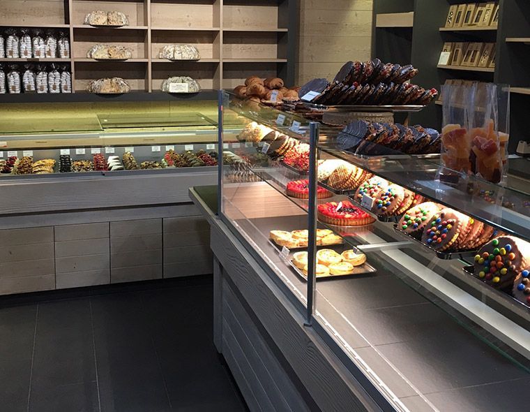 Vitrine de boulangerie avec pâtisseries et desserts, étagères remplies de pain.