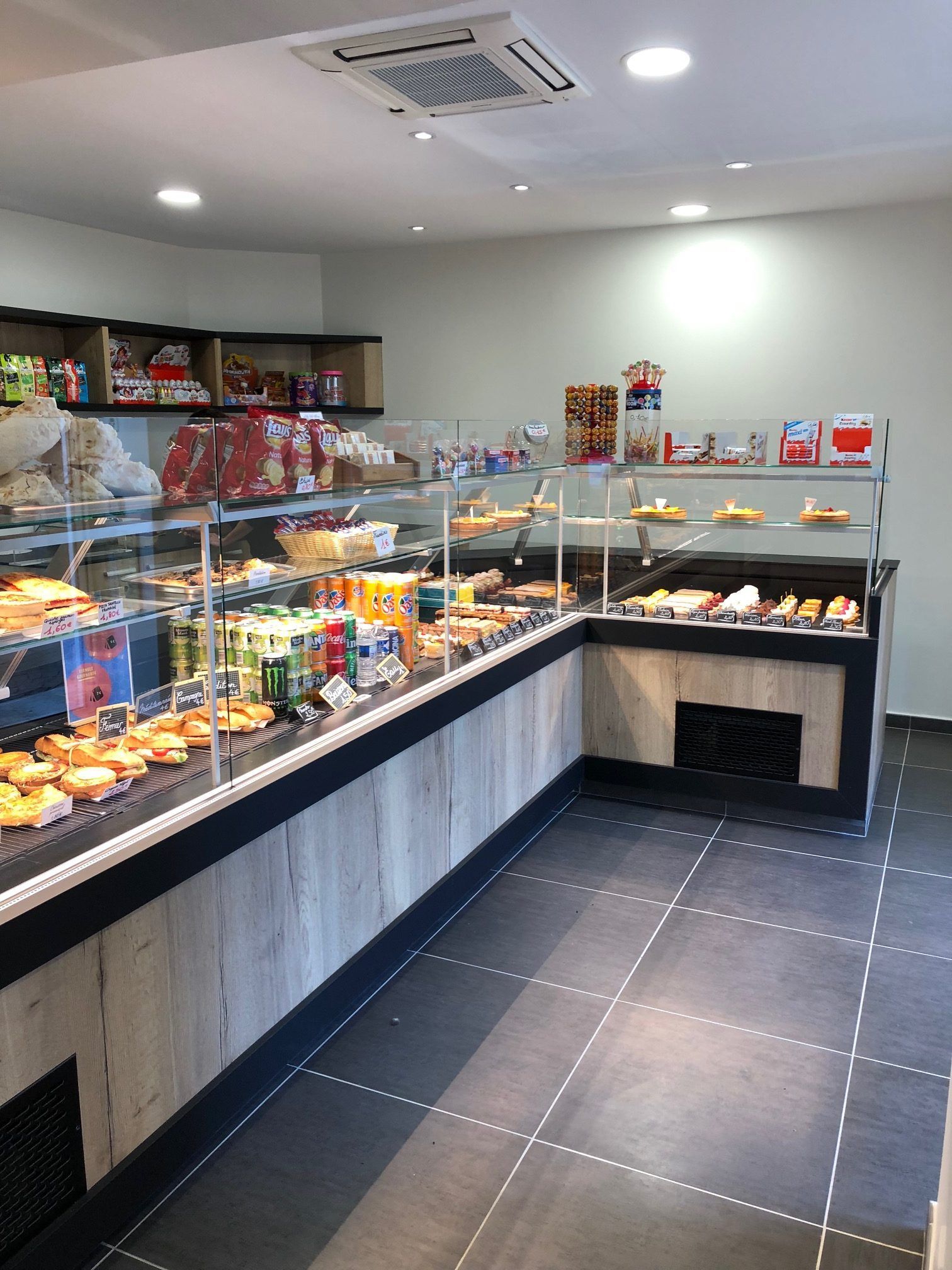 Intérieur d'une boulangerie avec une longue vitrine remplie de pâtisseries et de produits emballés.