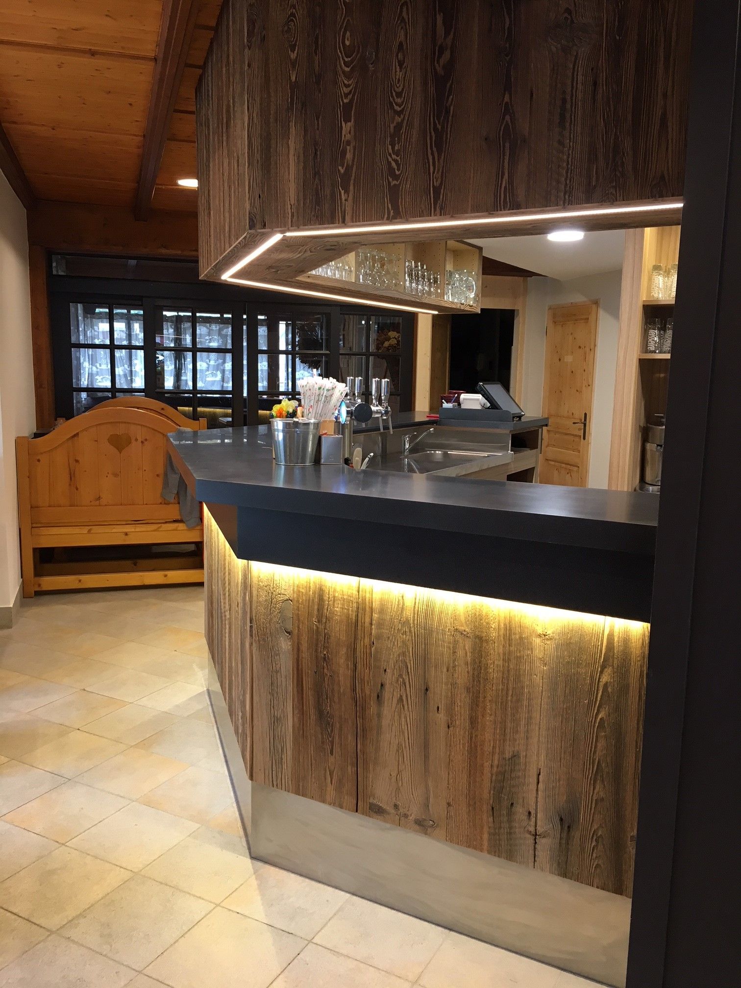 Bar en bois avec éclairage rétroéclairé, comptoir foncé et lambris rustique.