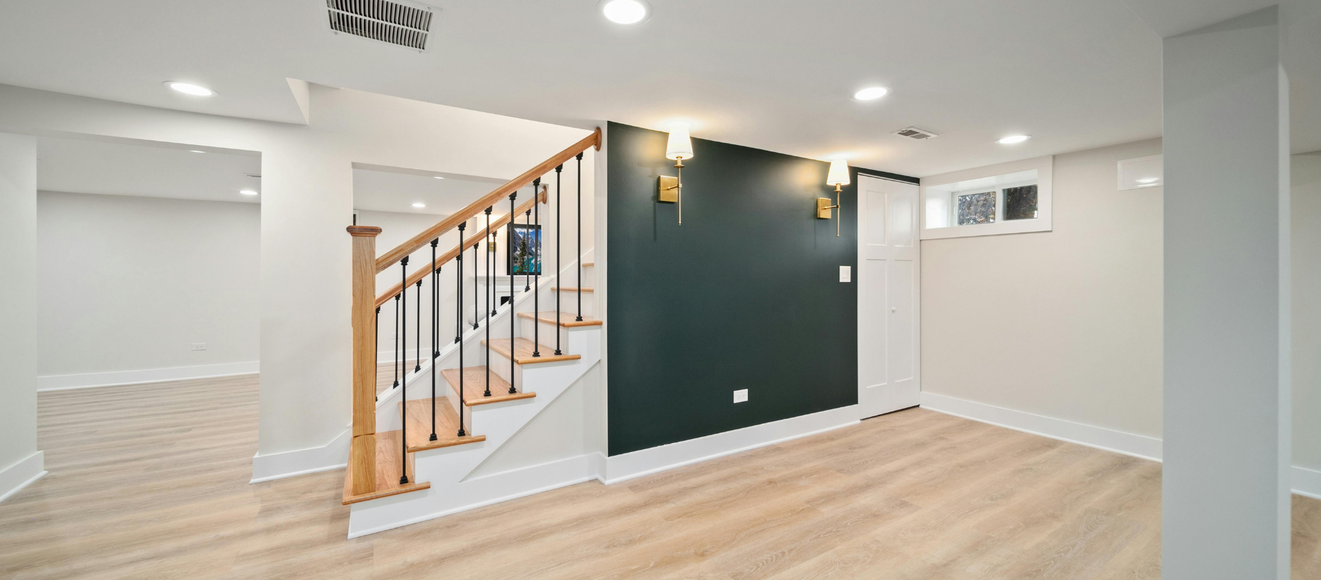 Un sous-sol récemment rénové avec un escalier et un mur d'accent vert foncé.