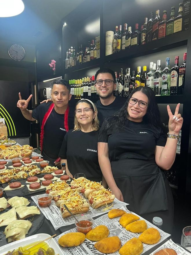 Dos mujeres están sentadas en una mesa comiendo sushi con palillos.