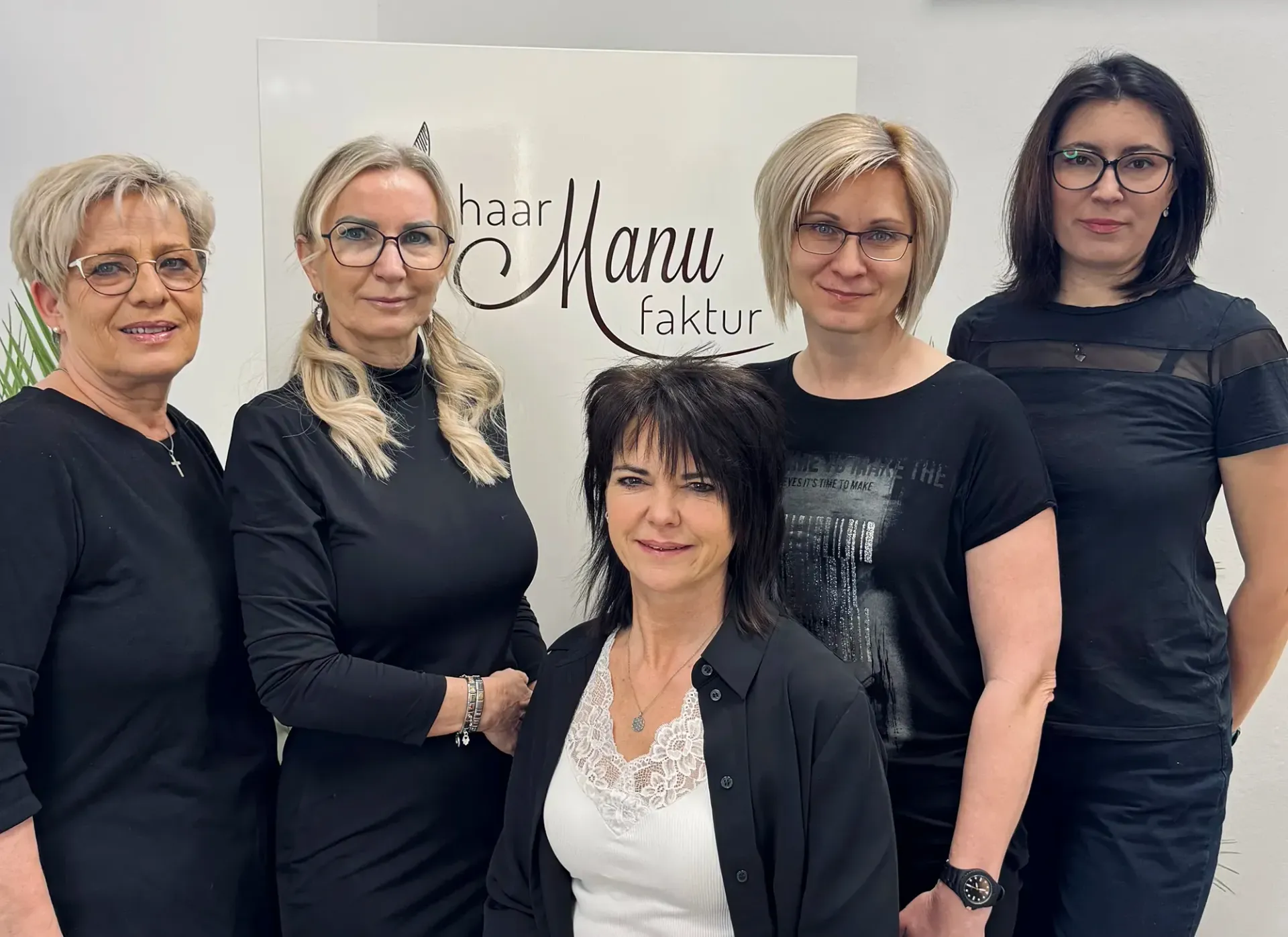 Eine Gruppe Frauen posiert für ein Foto vor einem Schild mit der Aufschrift „Manu“.
