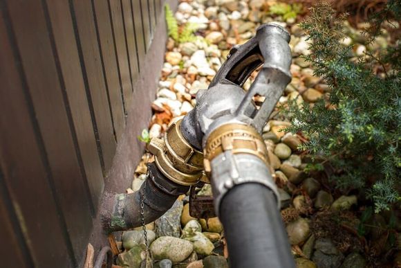 Tuyau de carburant raccordé à la façade d'un bâtiment, probablement pour la livraison de fioul.