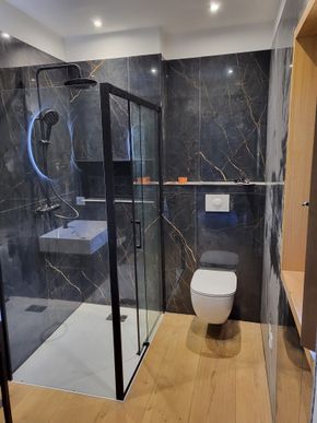 Salle de bains moderne avec murs en marbre, baignoire, meuble lavabo double vasque et miroir mural.