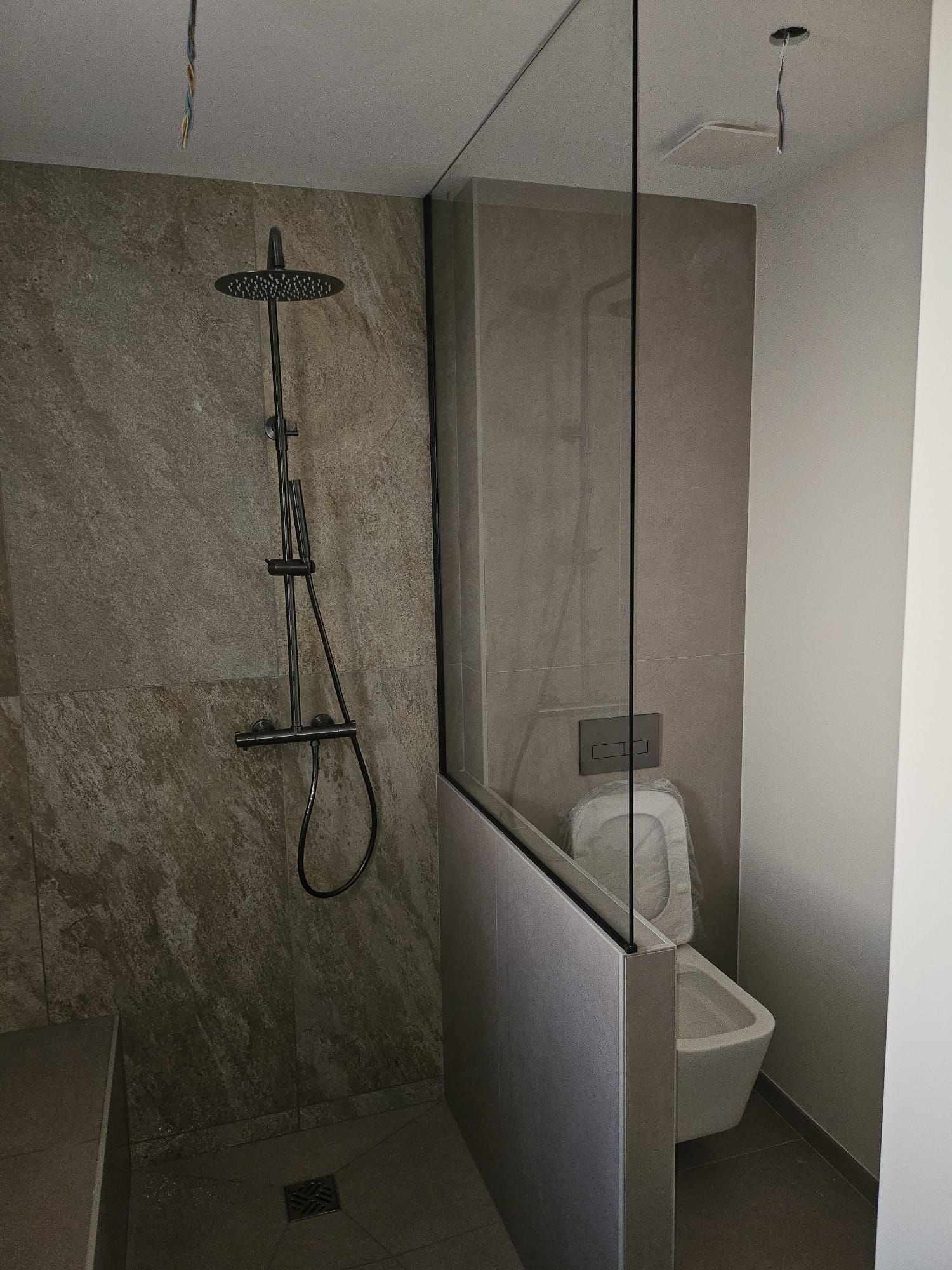 Salle de bains moderne avec douche à l'italienne, paroi de douche en verre, WC et lavabo suspendus.