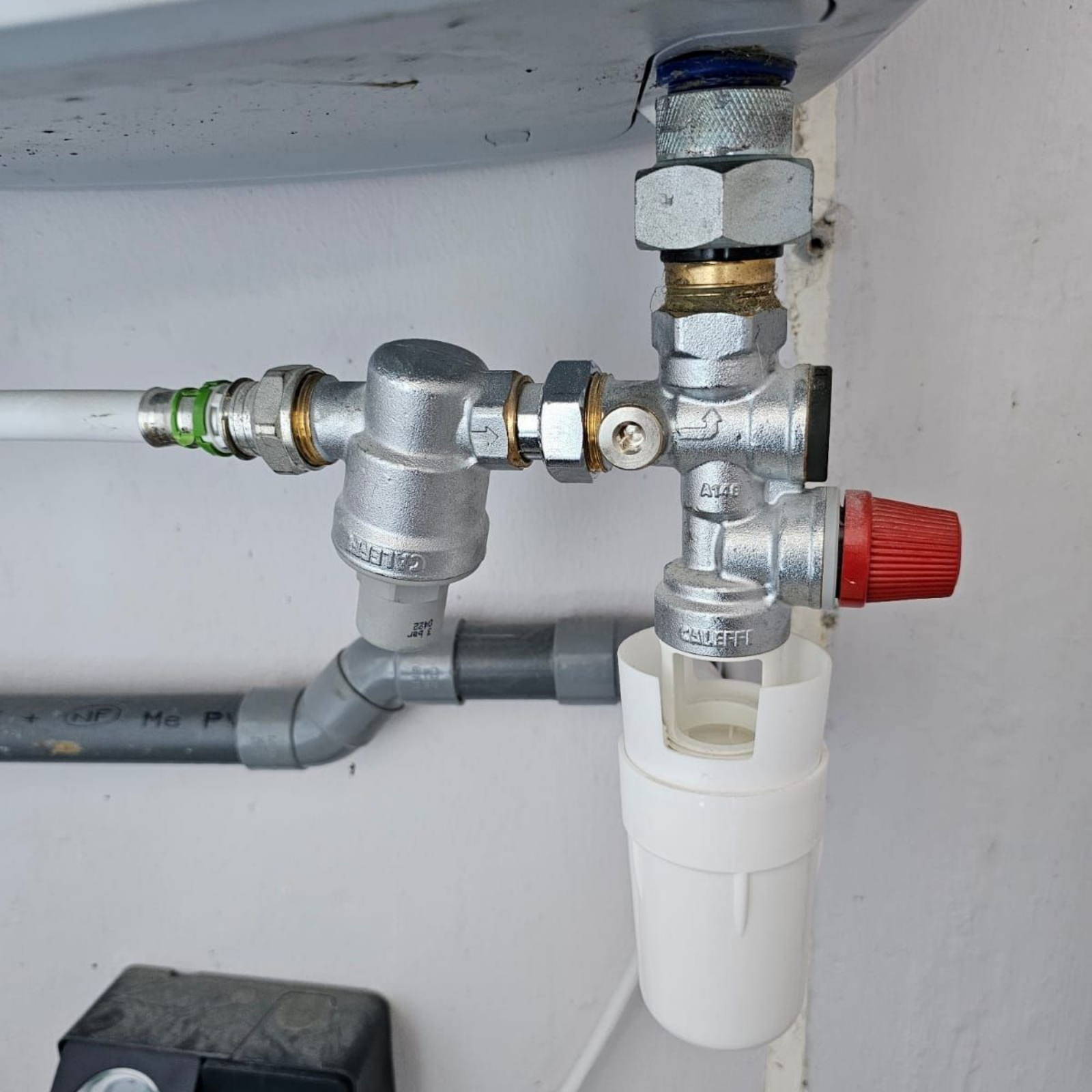 Étagère métallique avec tuyaux horizontaux et vannes dans un atelier industriel, adossée à un mur en treillis métallique.