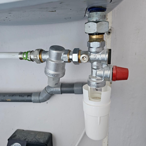 Robinets et tuyaux de plomberie sous évier avec boîtier de filtre blanc et bouton d'arrêt rouge