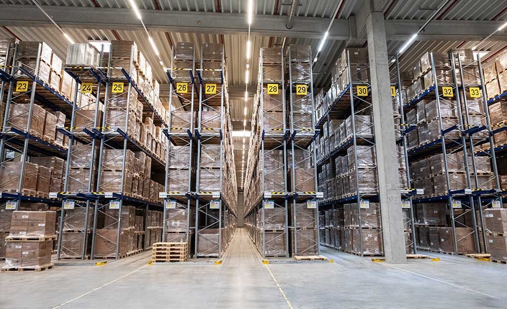Lagerinnenraum mit hohen Regalen voller Kisten, Gänge. Gelbe Zahlen kennzeichnen jeden Abschnitt.