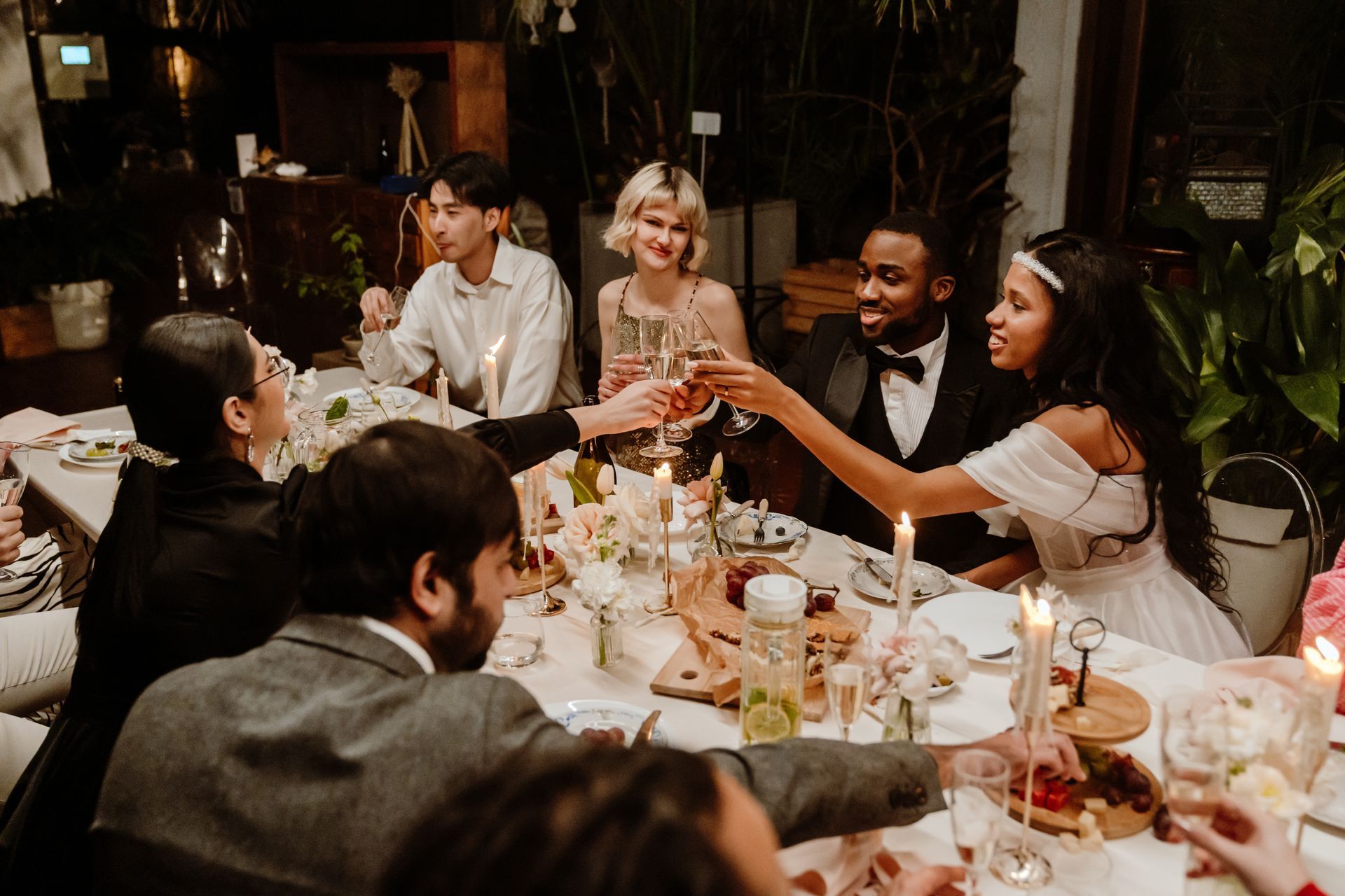 Les invités lèvent leurs verres lors d'un dîner chaleureux autour d'une table éclairée aux chandelles.