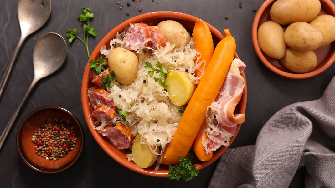 Bol de soupe de nouilles aux carottes, citron et herbes, accompagné d'une sauce et d'œufs durs, sur une table.
